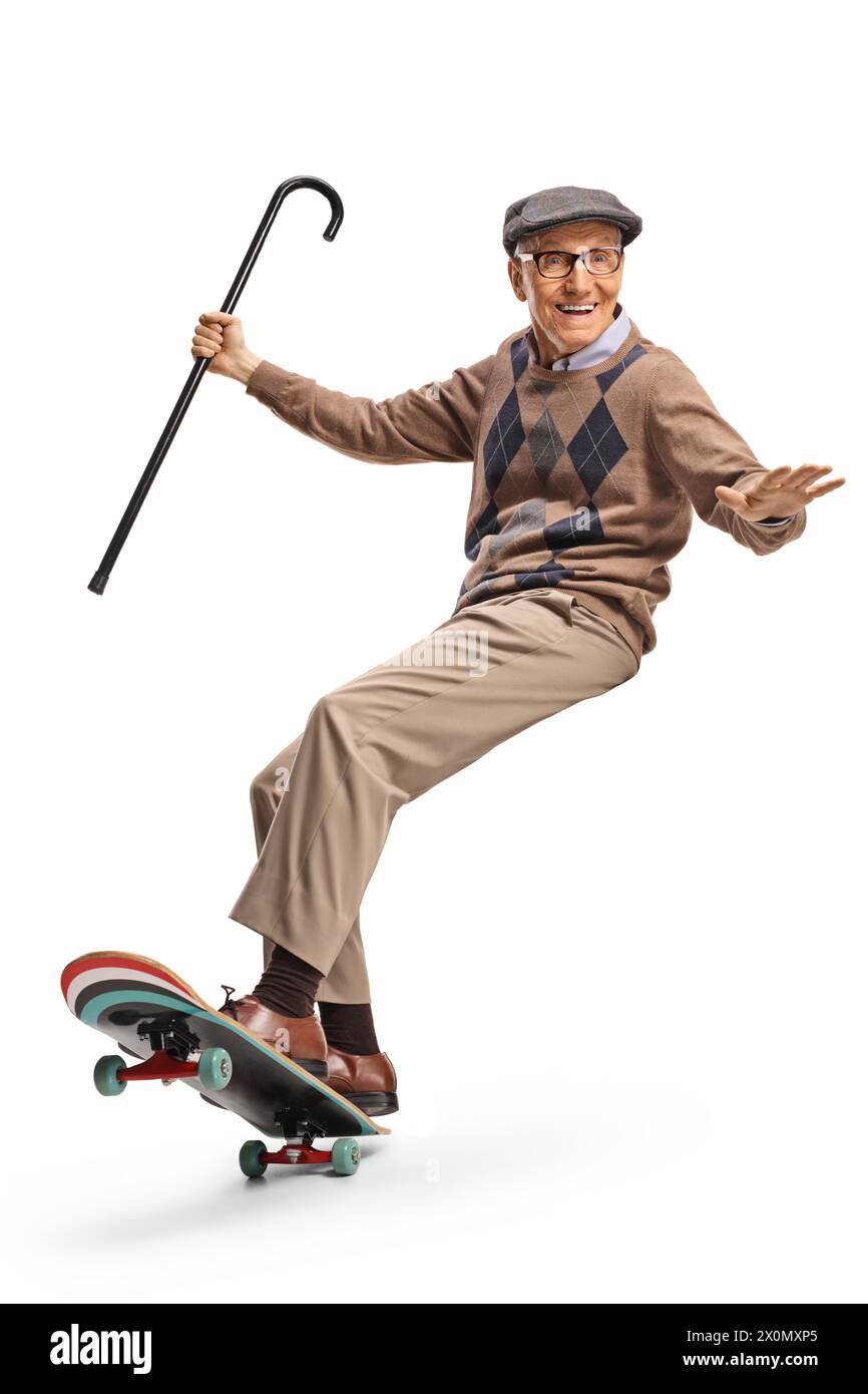 Homme âgé heureux chevauchant une planche à roulettes et tenant une canne isolée sur fond blanc Banque D'Images
