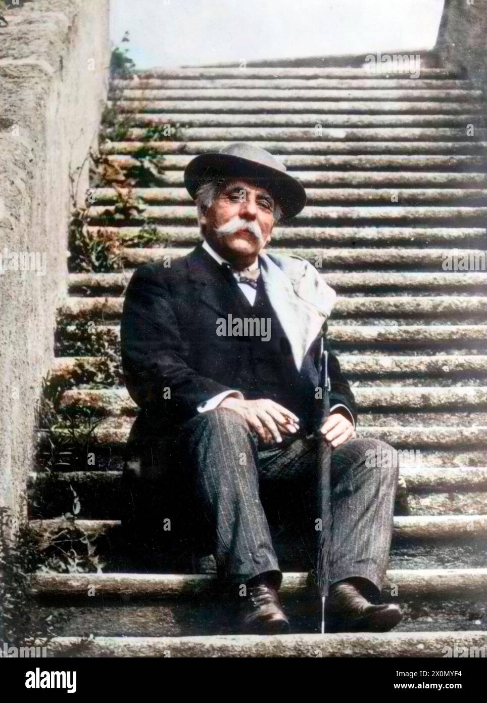 Gabriel Fauré assis sur un escalier, cigarette à la main - coloration ultérieure. Image colorée numériquement Banque D'Images