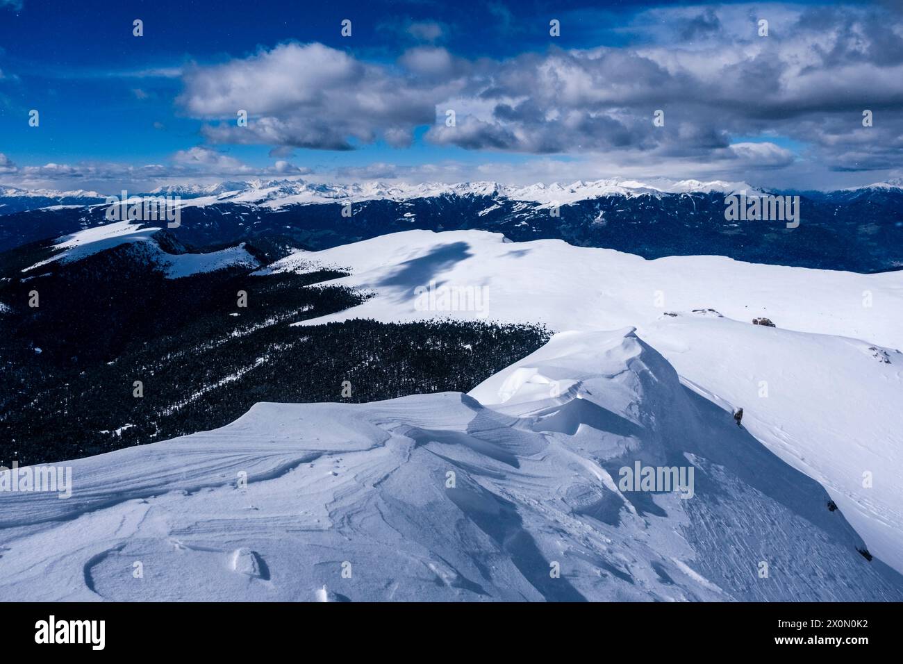 Pâturages enneigés au-dessous du sommet de Seceda en hiver, sommets de la chaîne principale des Alpes au loin. Banque D'Images