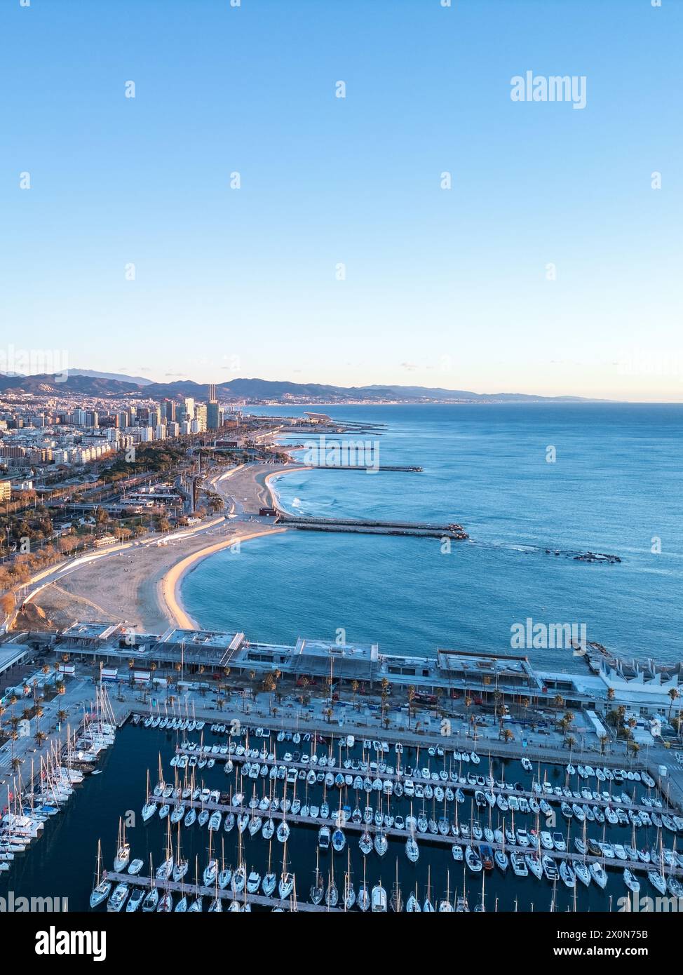 Plage de Barcelone en hiver. L'étreinte hivernale transforme la plage de Barcelone en un chef-d'œuvre tranquille tandis que le soleil se lève sur le sable immaculé Banque D'Images