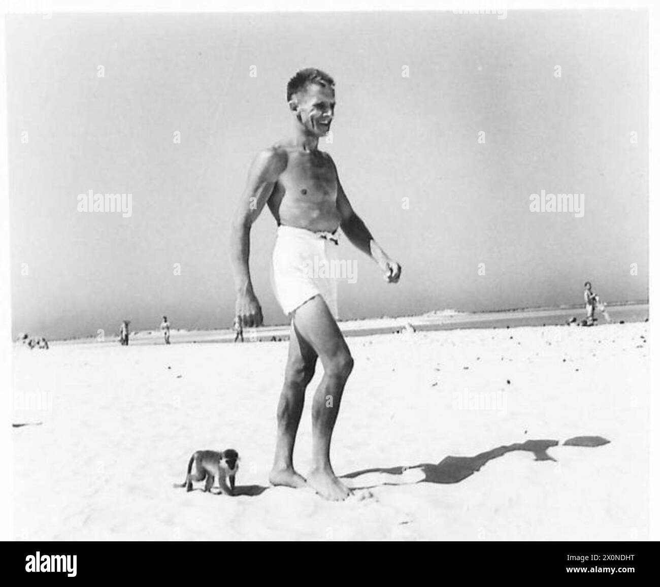 Un soldat court le long de la plage avec des hommes avant de se baigner, faisant preuve d'entraînement physique et de routines quotidiennes au sein de l'armée britannique. Banque D'Images