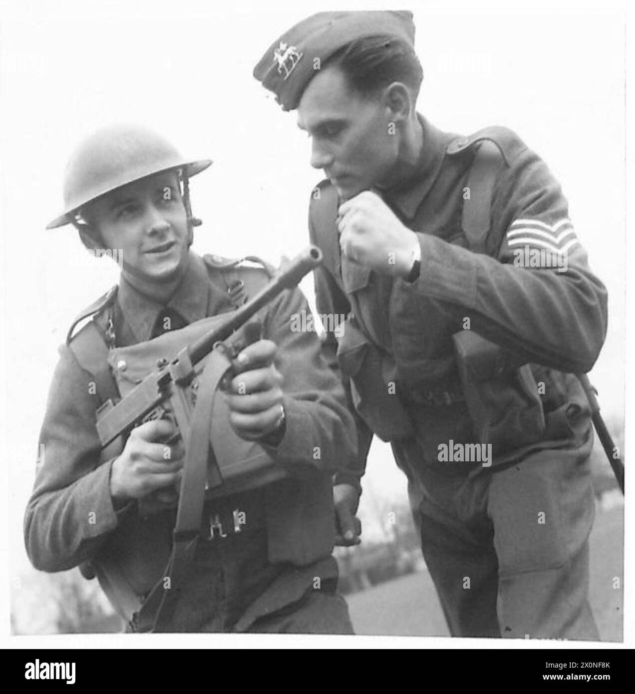 Dans un centre de formation d'infanterie, un sergent instructeur démontre l'utilisation d'un fusil tommy à un stagiaire, enregistré en négatif photographique. Banque D'Images