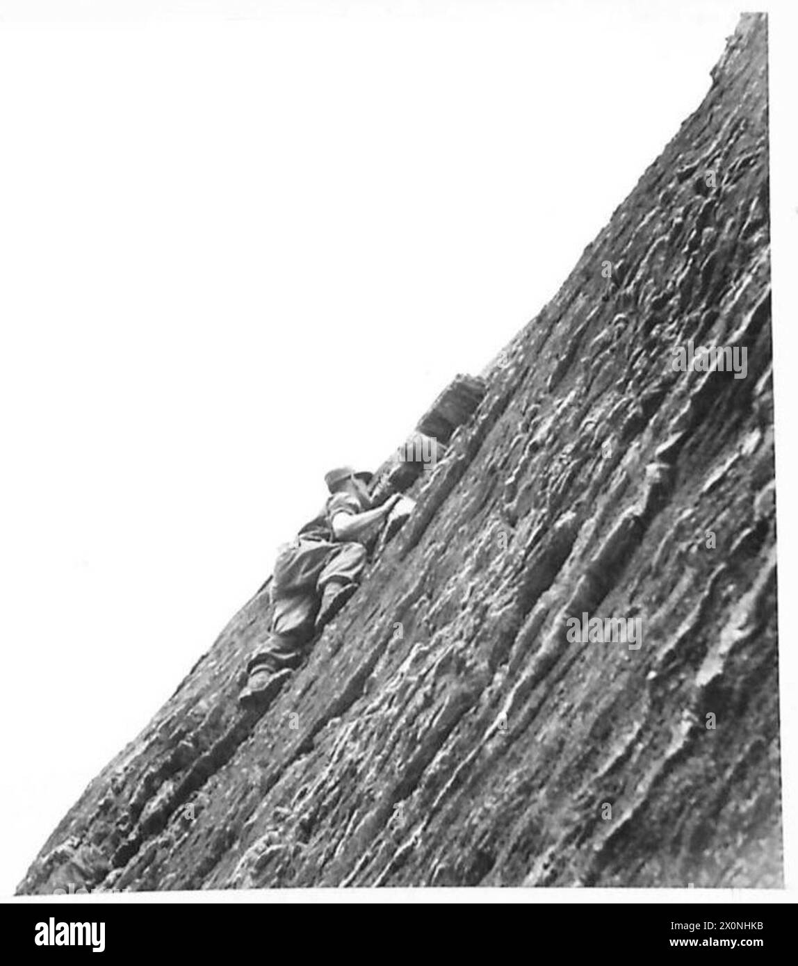 Les soldats connus sous le nom de Green Devils escaladent une falaise plate en utilisant les pieds disponibles. Négatif photographique, armée britannique. Banque D'Images