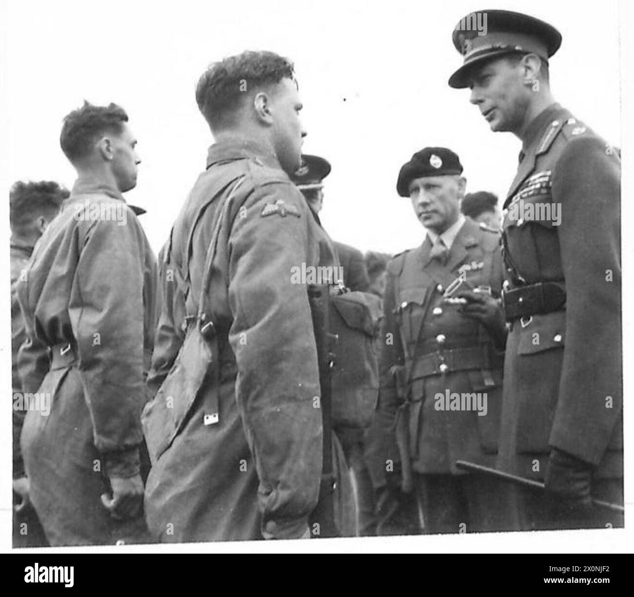 Négatif photographique montrant le roi parlant avec des parachutistes de l'armée britannique après un exercice de largage de parachute. Banque D'Images