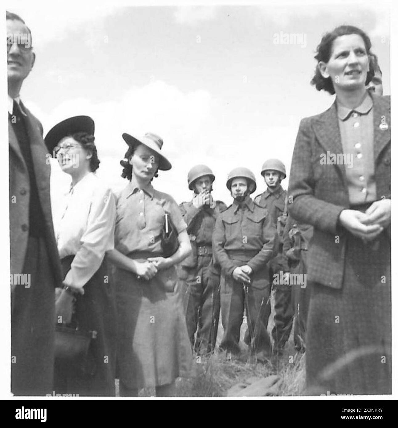 Photographie montrant des ouvriers d'usine observant une démonstration de parachutistes, avec des parachutistes effectuant des sauts et des manœuvres pendant l'exposition. Banque D'Images