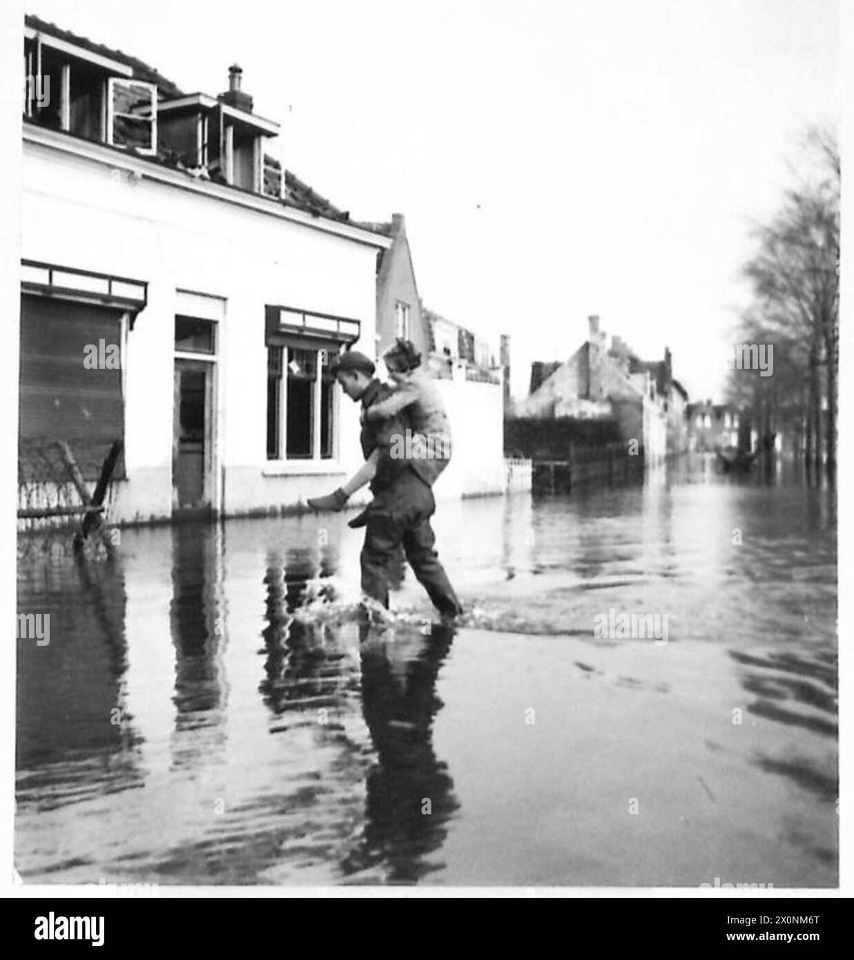 L'ÎLE INONDÉE DE WALCHEREN - Un soldat, chanceux d'être bien vêtu de cuissards, transporte une petite fille à travers les inondations. Négatif photographique, Armée britannique, 21e groupe d'armées Banque D'Images