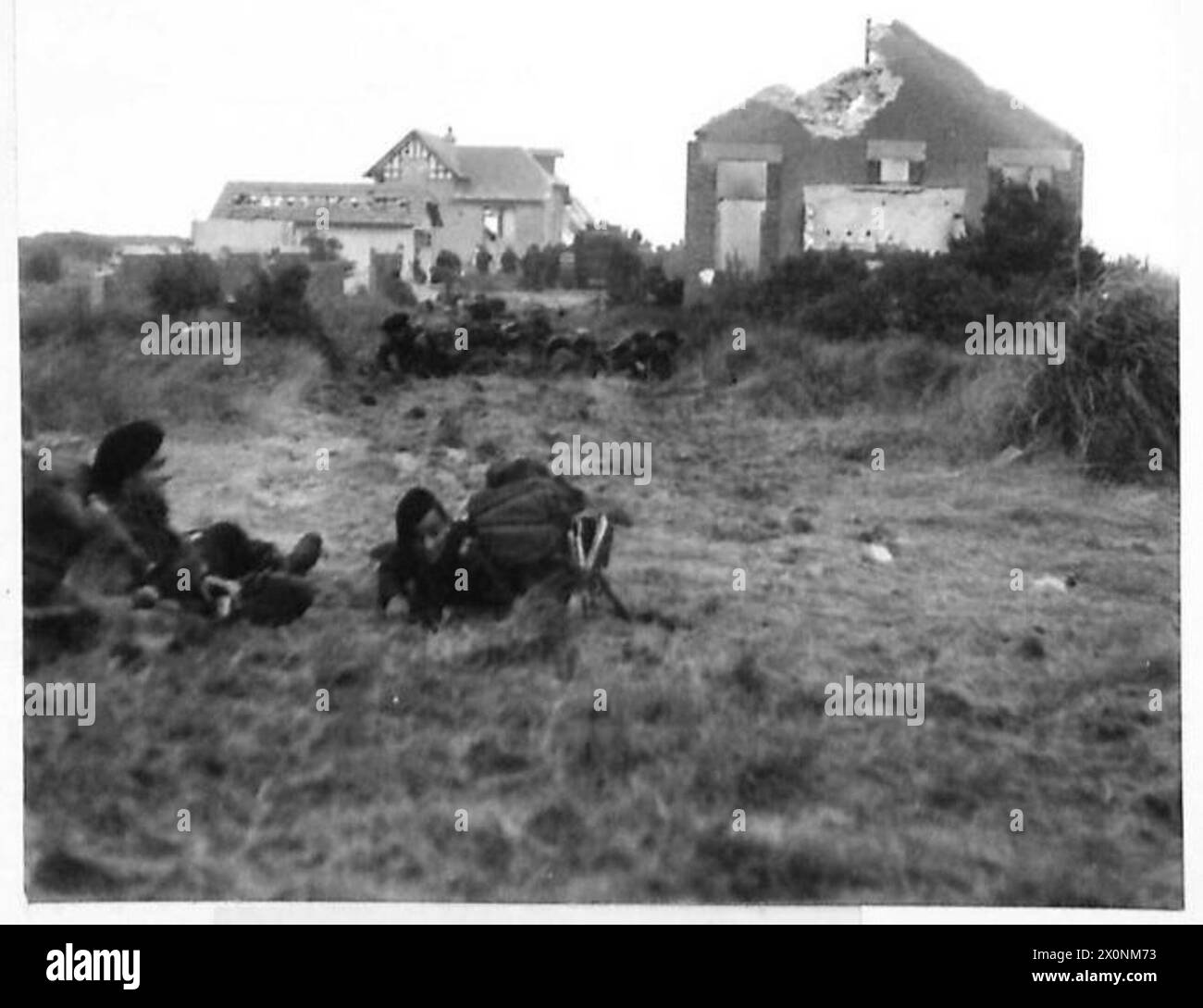 Des commandos de la 1re brigade de services spéciaux positionnés derrière Queen Red Beach, dans la région de Sword, en Normandie, le 6 juin 1944, avec des maisons endommagées et un Churchill AVRE en arrière-plan. Banque D'Images
