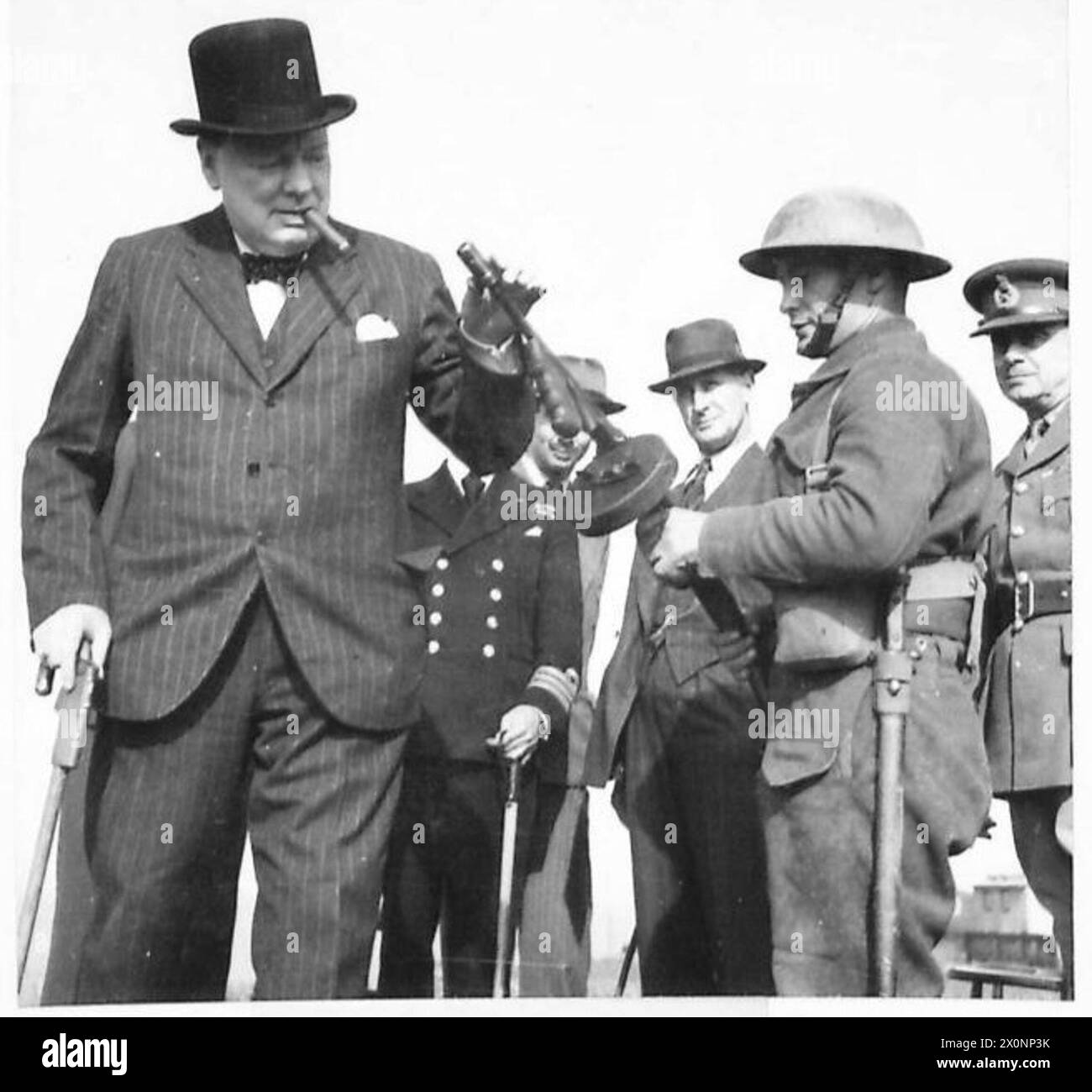Le premier ministre Winston Churchill examine un fusil Tommy et reçoit une explication de son mécanisme pendant qu'il parcourt les défenses militaires. Négatif photographique, armée britannique. Banque D'Images