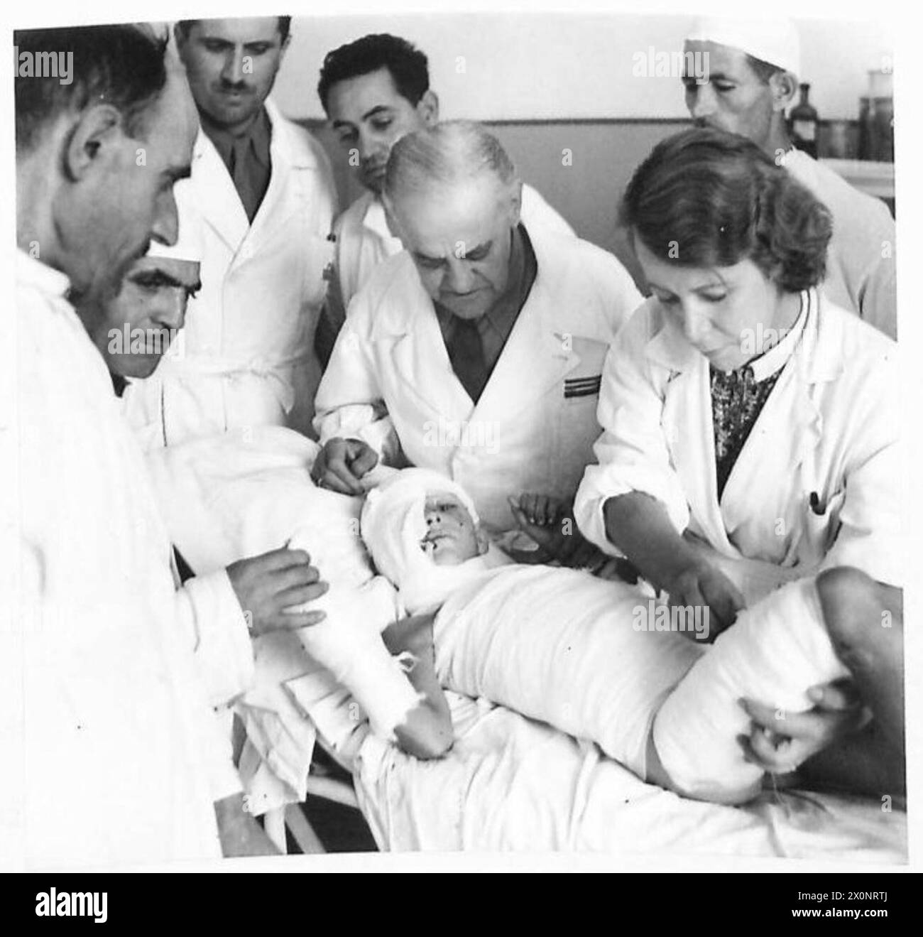 Le personnel de la Croix-Rouge italienne fournit des soins médicaux aux blessés yougoslaves en Italie. Nada Marusic, 9 ans, blessée alors qu'elle portait des munitions, reçoit des soins dans une salle d'opération dispensés par des médecins et des infirmières. Banque D'Images