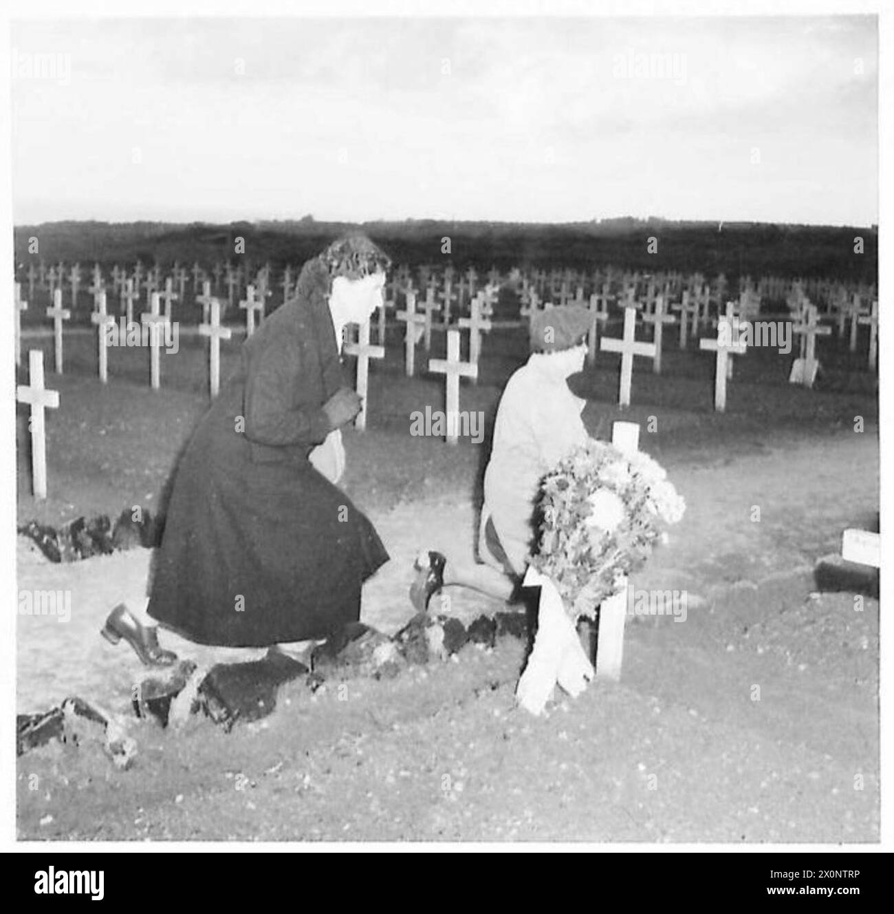 LES ITALIENS HONORENT ALLIED FALLEN - une femme italienne au premier plan de l'image, après avoir placé des fleurs sur la tombe d'un soldat britannique, tombe sur ses genoux et prie. Négatif photographique, Armée britannique Banque D'Images