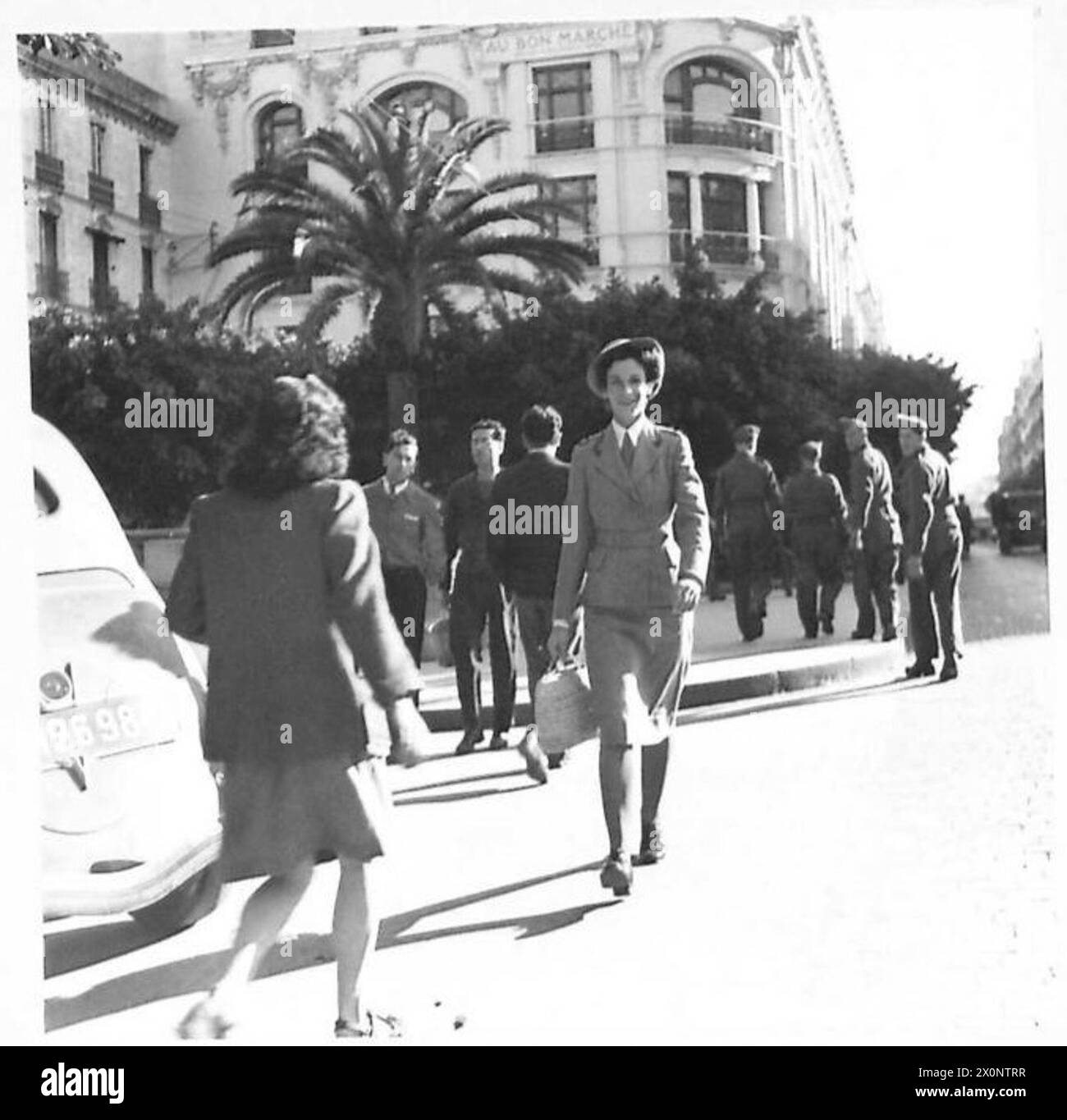 Photographie de sœur Langridge, infirmière en Afrique du Nord, marchant dans un centre commercial d'Alger pendant son jour de congé tout en recevant l'attention des troupes britanniques. Banque D'Images
