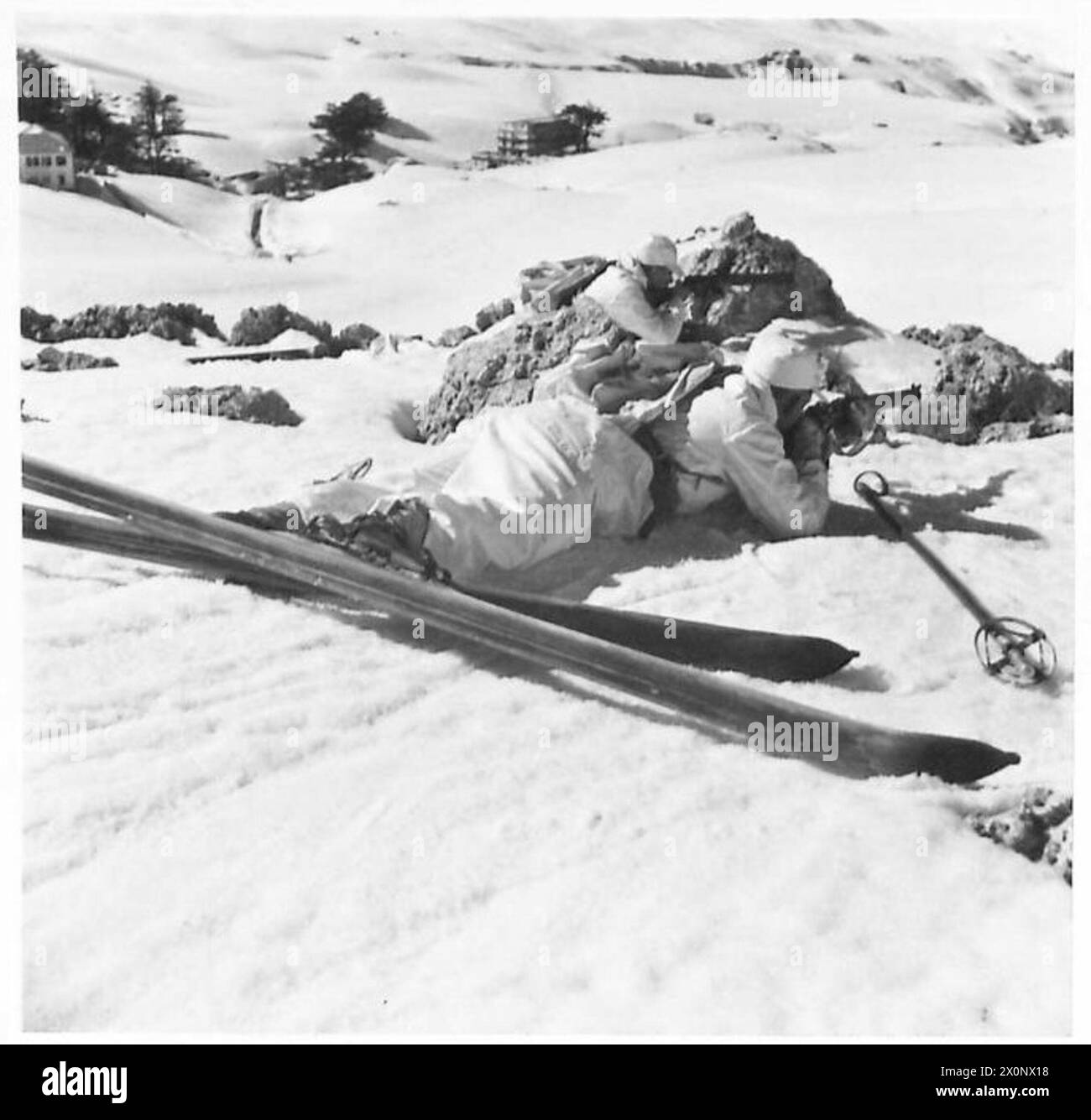 Les troupes de ski se mettent à couvert derrière les rochers sur un terrain enneigé pendant les exercices d'entraînement, démontrant les tactiques de terrain et la préparation. Banque D'Images