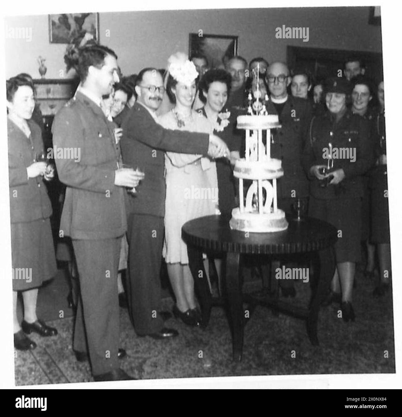 La mariée et le marié sont représentés coupant le gâteau de mariage à l'église de garnison d'Iserlohn, entourés d'invités. La photographie capture une célébration de mariage de l'armée britannique en Allemagne. Banque D'Images La mariée et le marié sont représentés coupant le gâteau de mariage à l'église de garnison d'Iserlohn, entourés d'invités. La photographie capture une célébration de mariage de l'armée britannique en Allemagne. Banque D'Images