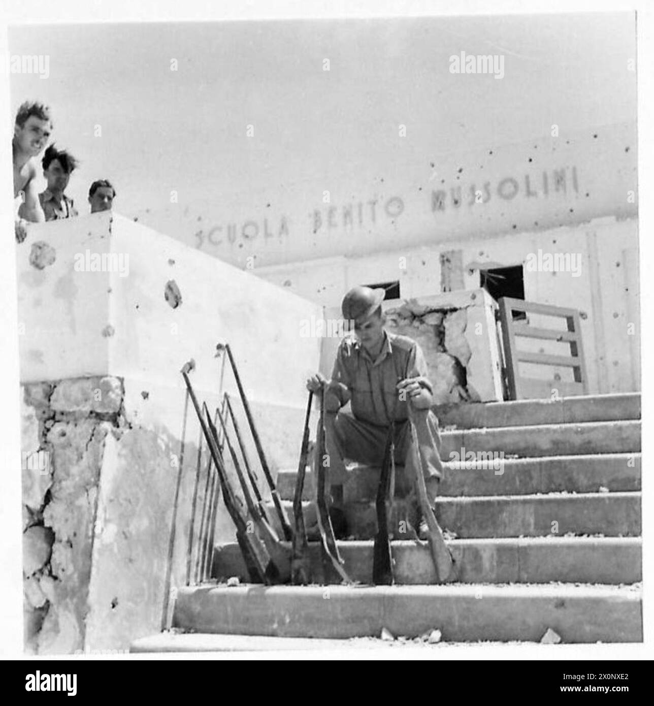 Photographie montrant un soldat manipulant des fusils factices dans une école italienne, utilisés à des fins d'entraînement par l'armée britannique. Banque D'Images