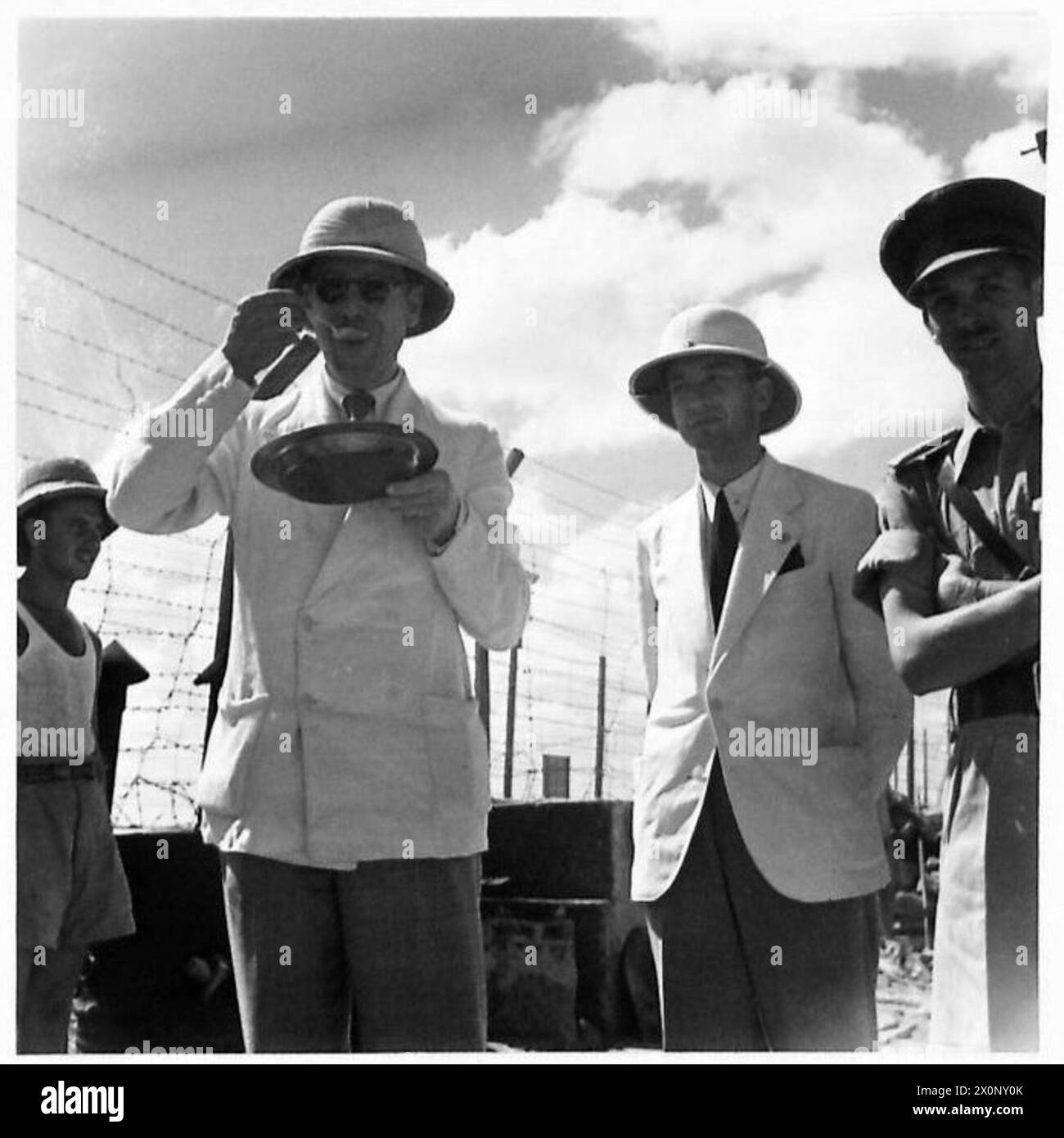 Mr. de Haller, représentant du Comité international de la Croix-Rouge, déguste de la soupe dans une cuisine de camp de P.O.W. au moyen-Orient avec Mr. J. Duchosal et le médecin du camp, documentant la surveillance humanitaire. Négatif photographique de l'armée britannique. Banque D'Images