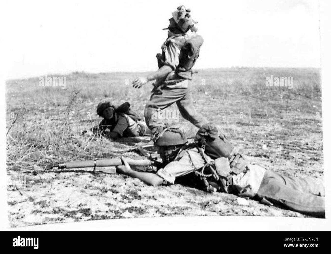 Au cours d'un exercice de la division aéroportée, deux parachutistes reposent dans un pli au sol tandis qu'un troisième lance une grenade No.36. Négatif photographique, armée britannique. Banque D'Images