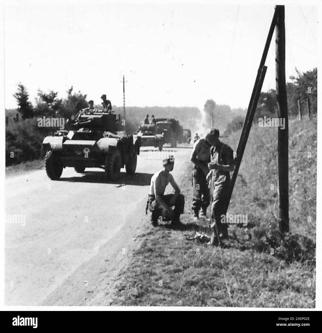 Les signaleurs posent des fils téléphoniques sur un seul pont Bailey tandis que les voitures blindées se déplacent le long de la route près de Laurent de Condel. Banque D'Images