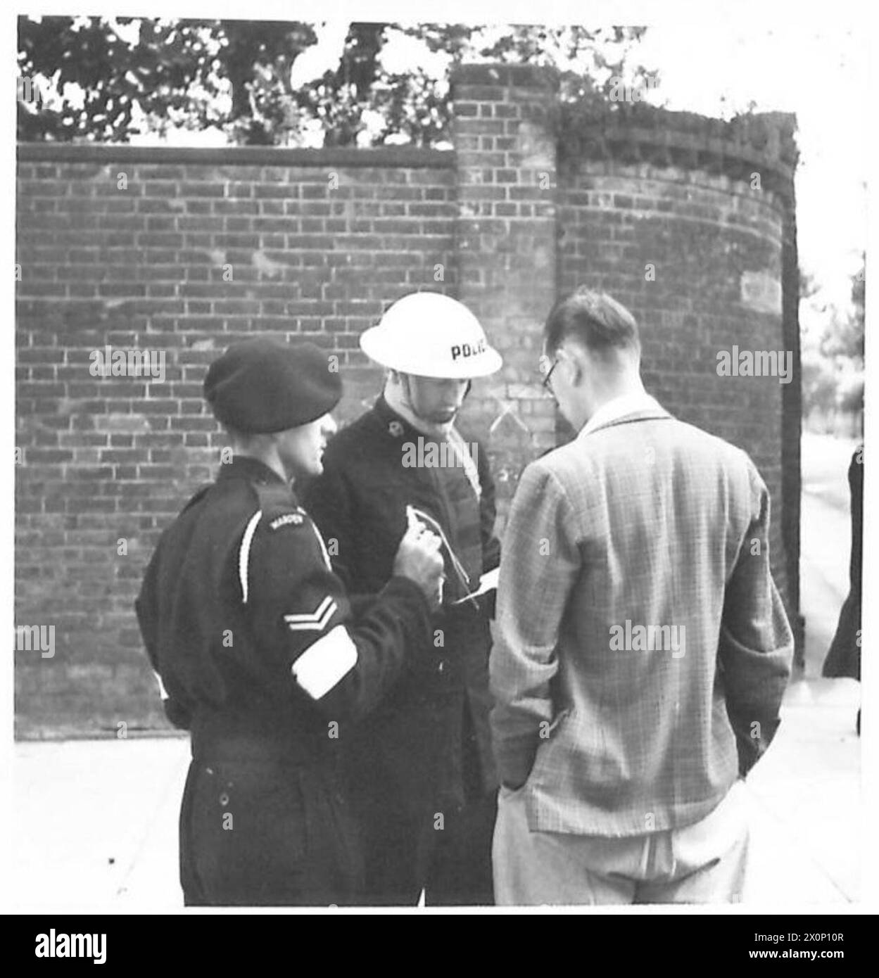 Un inspecteur de police et un juge-arbitre examinent les procédures à un barrage routier pendant les exercices de formation de la Home Guard et de la protection civile. Banque D'Images