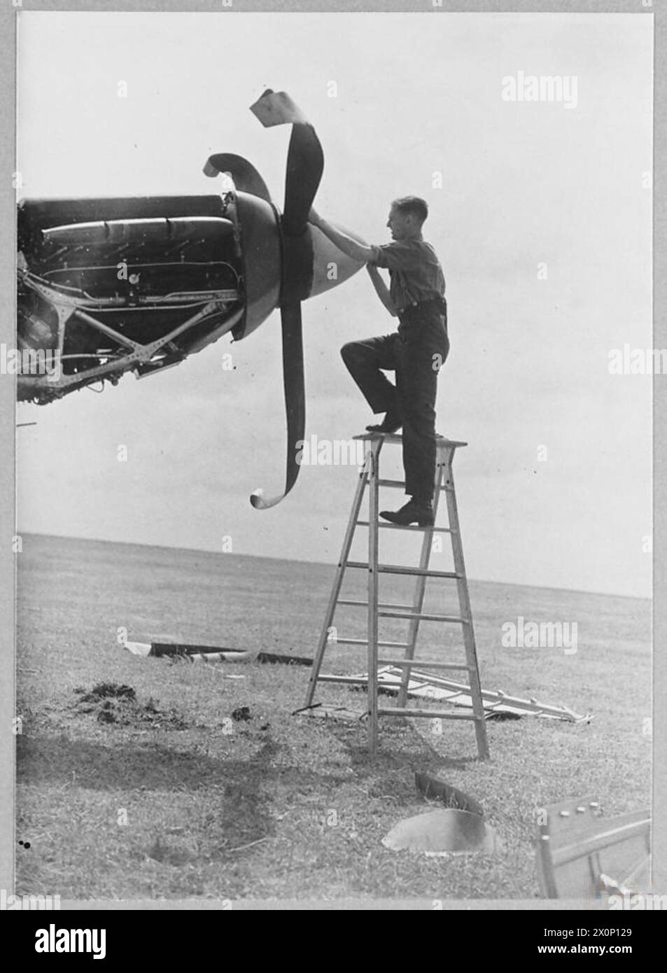 Un aviateur inspecte le nez d'un Boulton Paul Defiant endommagé lors d'un écrasement à Manston en mai 1940. L'aéronef peut être de type L7019 piloté par le pilote-officier R.W. Stokes. Négatif photographique émis par la Royal Air Force. Banque D'Images