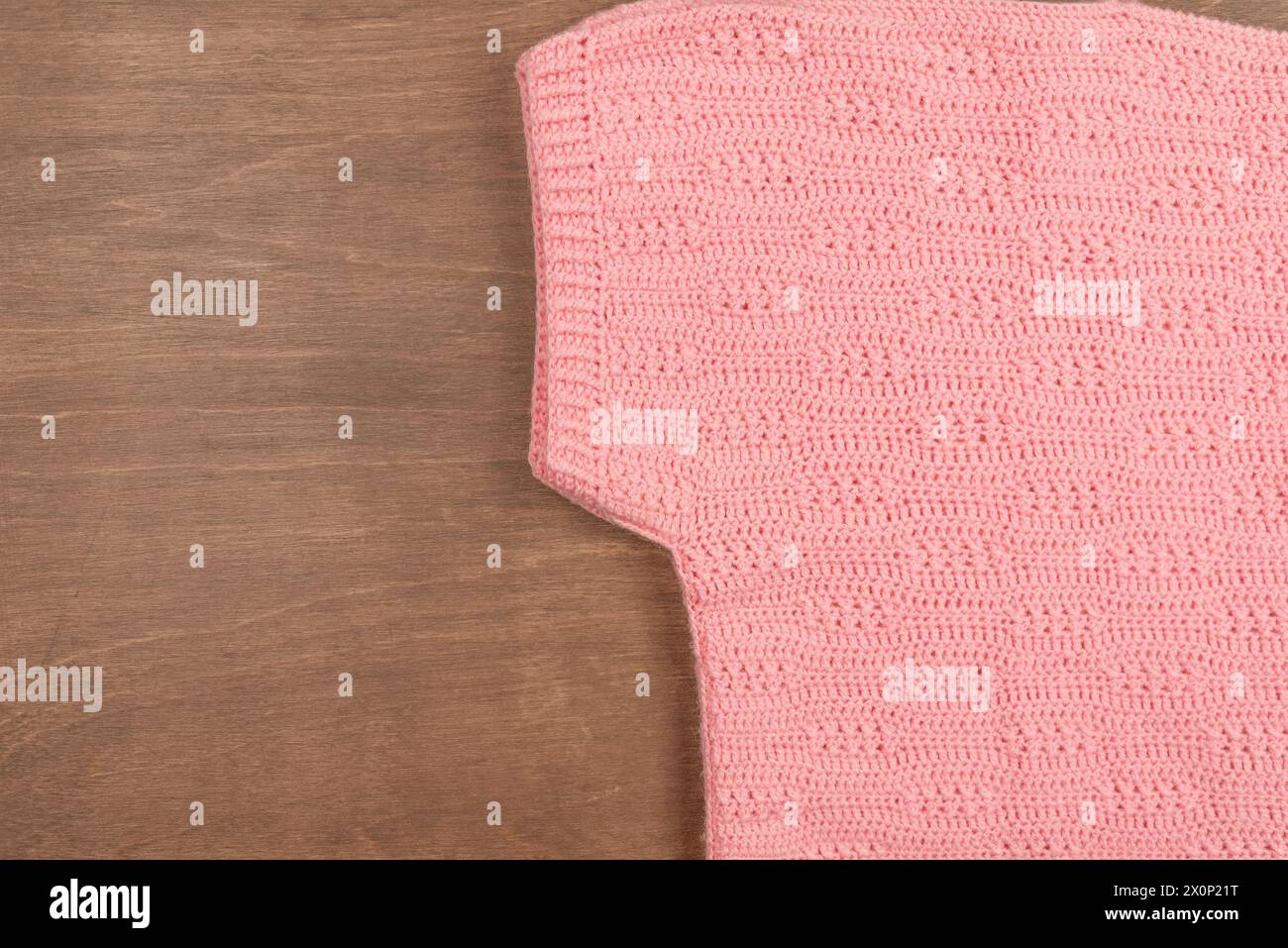 Pull chaud en laine rose tricoté d'hiver sur un fond en bois Banque D'Images