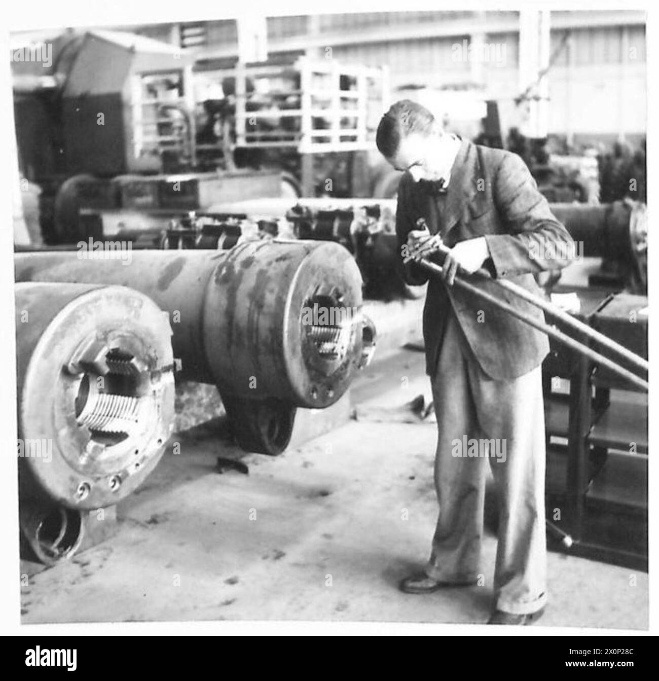Le personnel mesure le tunnel d'un canon de 6 pouces dans un dépôt de munitions pour la maintenance et l'inspection. Banque D'Images
