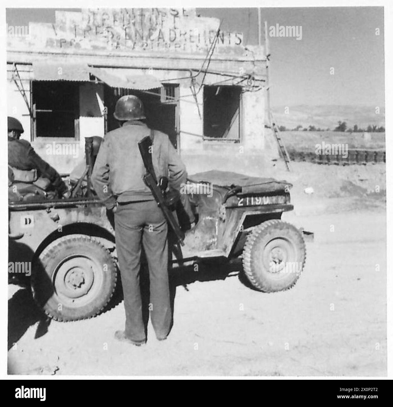 Les troupes américaines et britanniques se tiennent près d'une jeep à Medjez el Bab le 5 décembre 1942 pendant la campagne de Tunisie. Un soldat américain porte un pistolet Tommy avec un chargeur rond. Banque D'Images