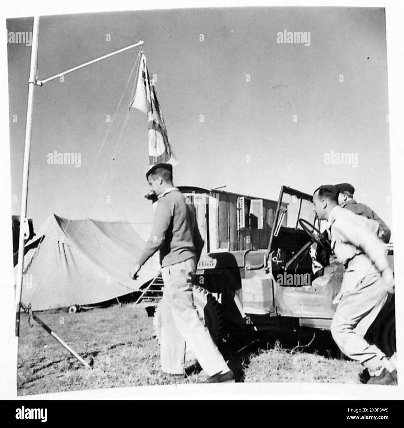 Un officier d'infanterie arrive dans une jeep à la salle des opérations de l'escadre, avec une vieille caravane de travailleurs de la route découverte sur l'aérodrome de Foggia pendant les opérations de la 8e Armée. Négatif photographique, armée britannique. Banque D'Images