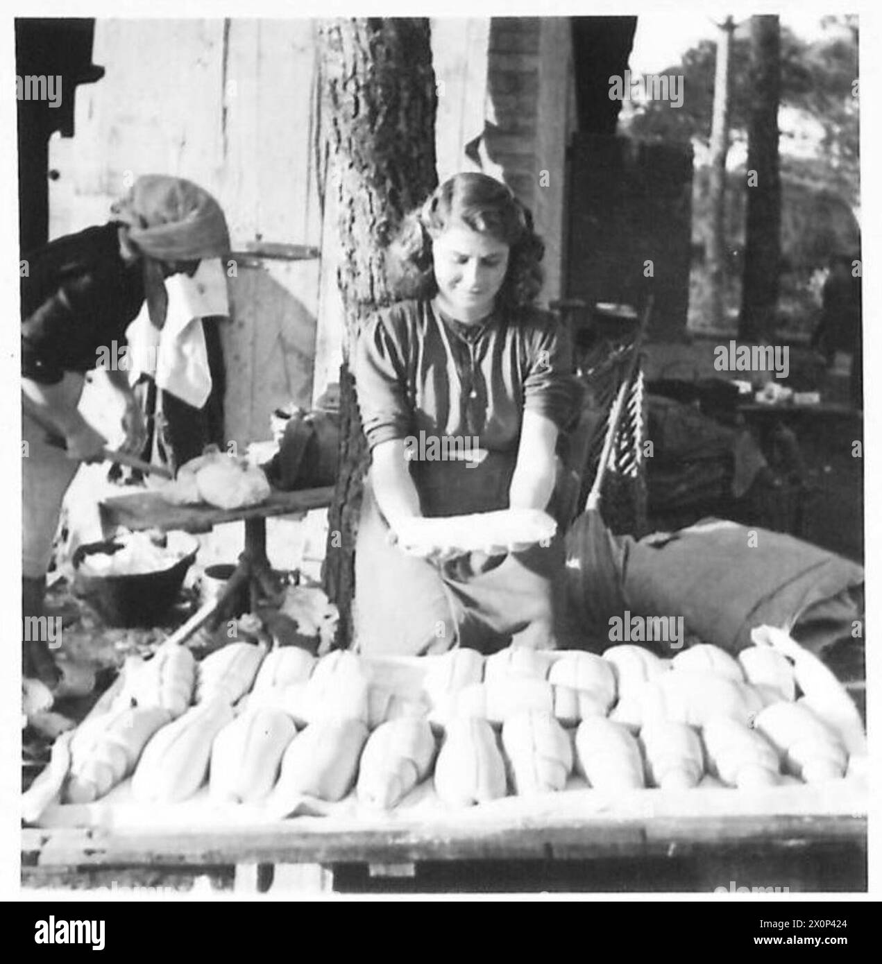 Négatif photographique montrant une jeune italienne préparant un pain moulé cuit sur place alors qu'elle vivait avec des partisans. Banque D'Images