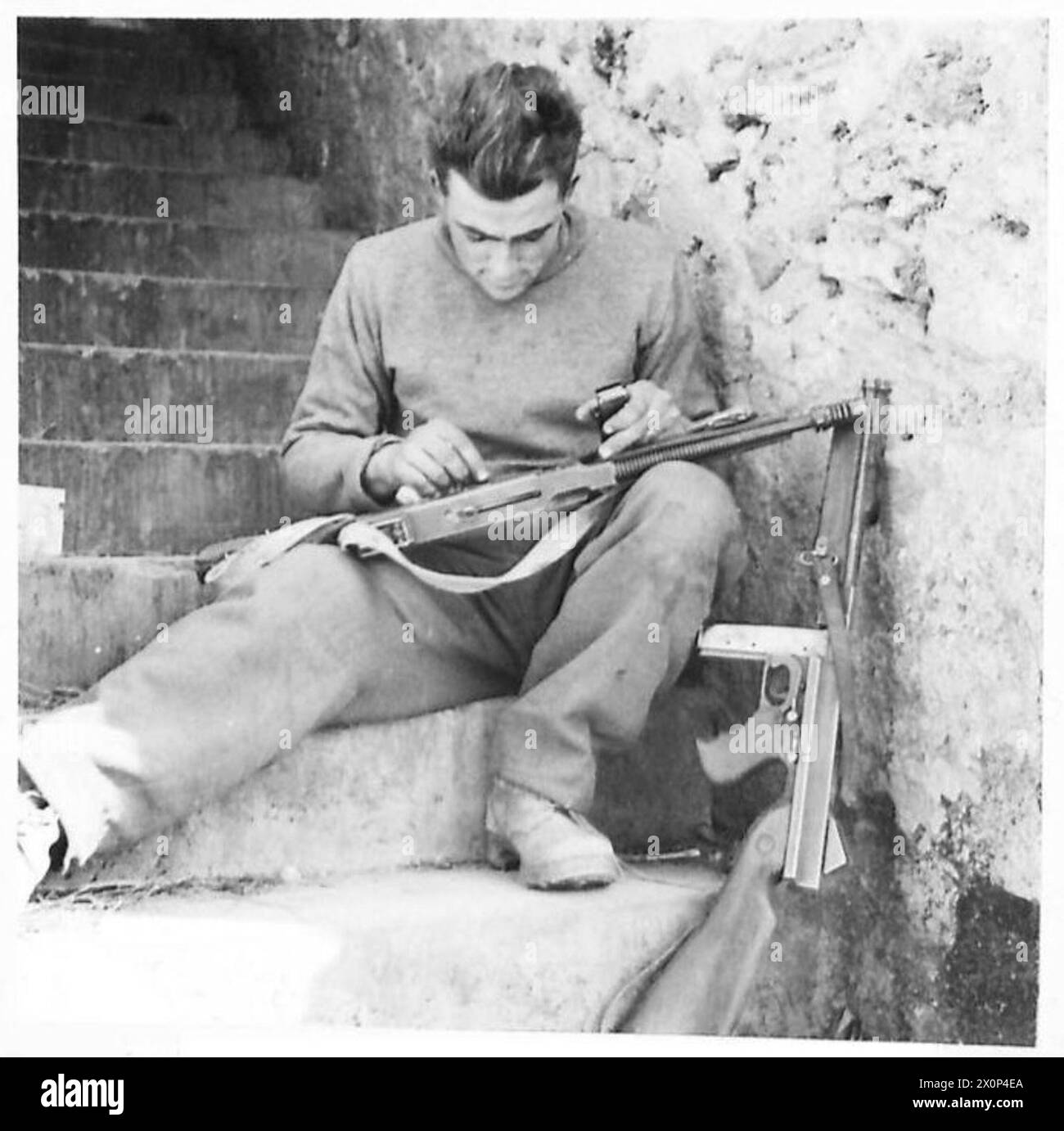 Négatif photographique montrant le caporal Syd Bubb du 25e bataillon de la 6e brigade d'infanterie néo-zélandaise nettoyant des armes tout en se déplaçant à travers des décombres à Cassino la nuit pendant les opérations de la 5e armée. Banque D'Images