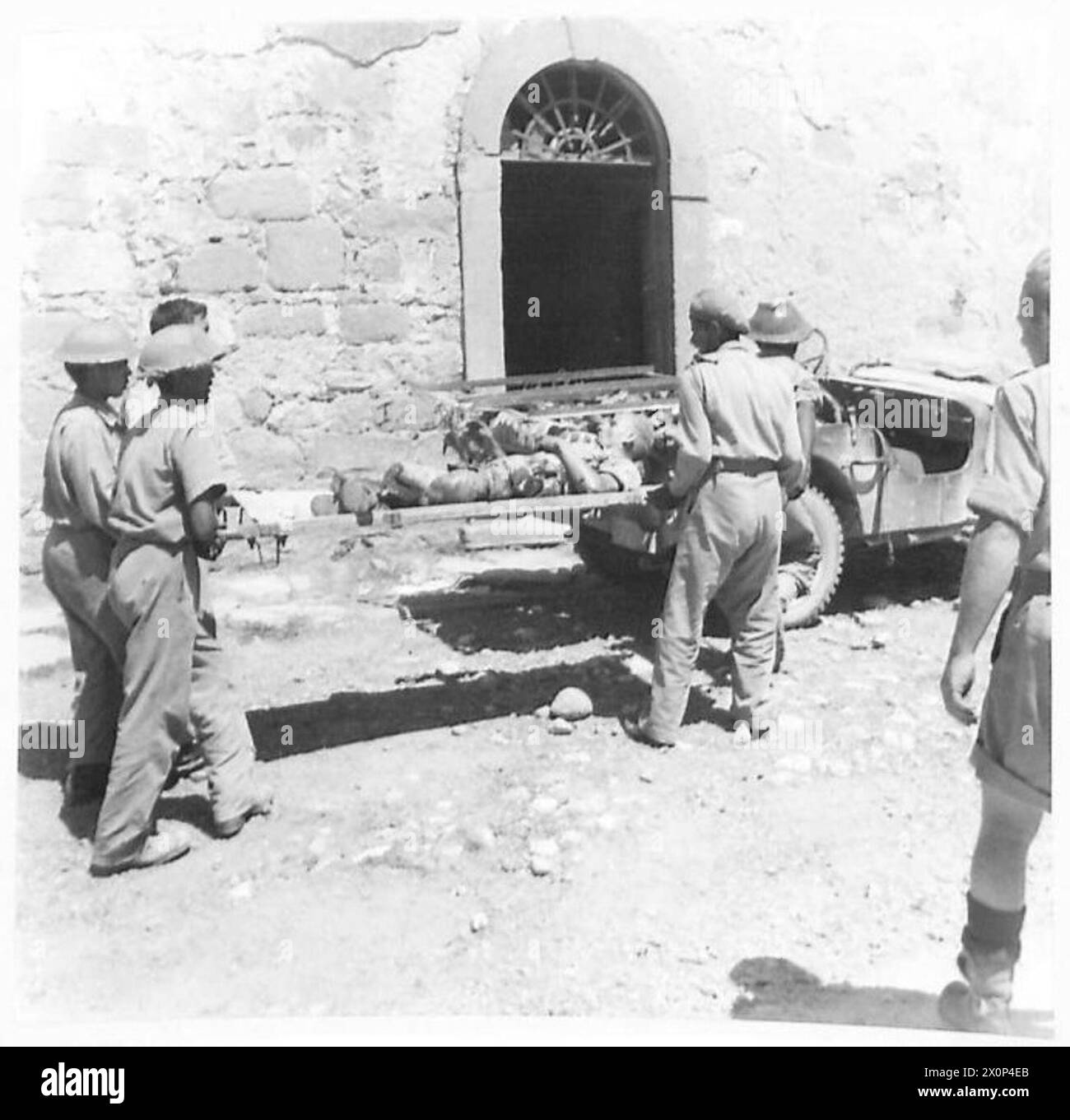 La route d'Anghiari est sous les tirs d'obus ennemis. Un cavalier blessé est assisté par des porteurs de brancards indiens de la 25e division dans une jeep ambulance. Banque D'Images