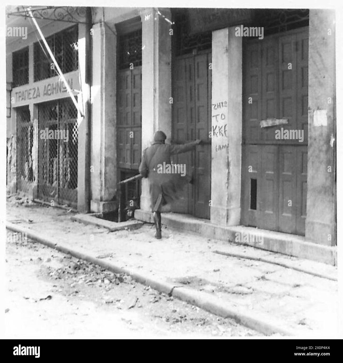 GRÈCE : RECONNAISSANCE DE COMBAT DE JOUR - Un policier grec pénètre dans un bâtiment pour rechercher des troupes de l'E.L.A.S. Il est couvert par un char Sherman, dehors dans la chaussée. Négatif photographique, Armée britannique Banque D'Images