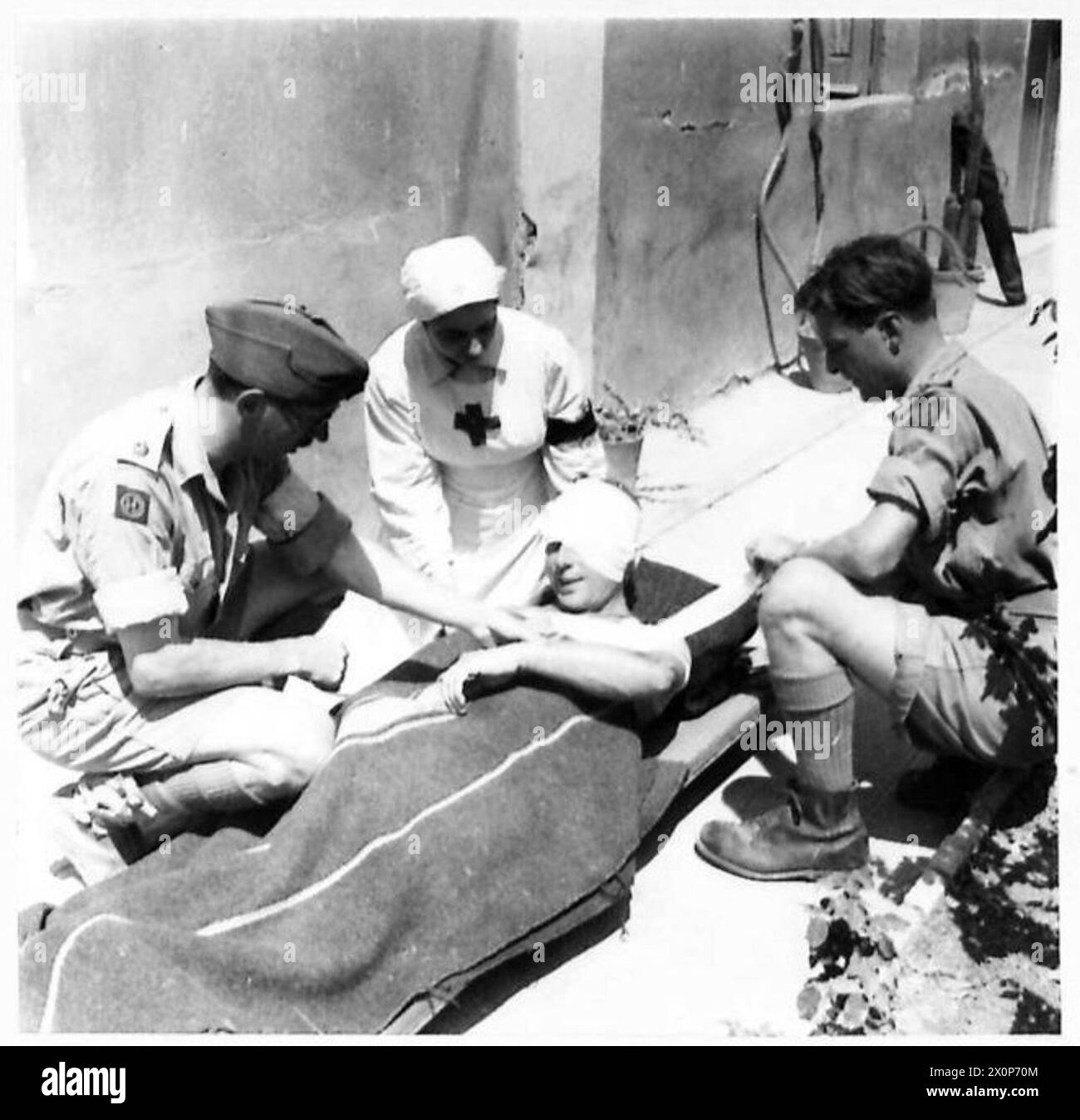 À Rammacca, des infirmières de la Croix-Rouge italienne assistent le personnel du R.A.M.C. L'infirmière Yolanda Girasole aide à habiller les blessés britanniques aux côtés du major G.A. Fowler et du capitaine J.S. Hutchinson. Les négatifs photographiques documentent le soutien médical et les opérations hospitalières de campagne. Banque D'Images