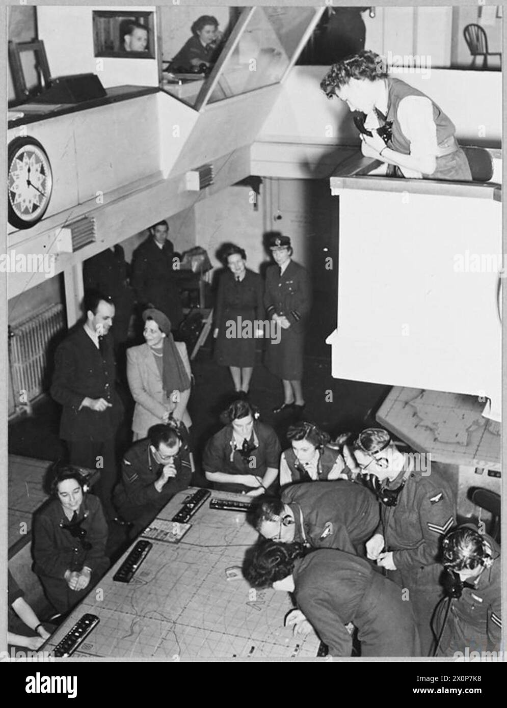 ÉPOUSE DU MINISTRE BRÉSILIEN DE L'AIR AU COMMANDEMENT DU CHASSEUR H.Q. - pour l'histoire voir CH.16285 image émise 1945 spectacles - regarder le personnel au travail dans la salle des filtres, où tous les mouvements d'avions, reçus de tous les types de détecteurs, sont enregistrés et l'information transmise à la salle des opérations. Négatif photographique, Royal Air Force Banque D'Images