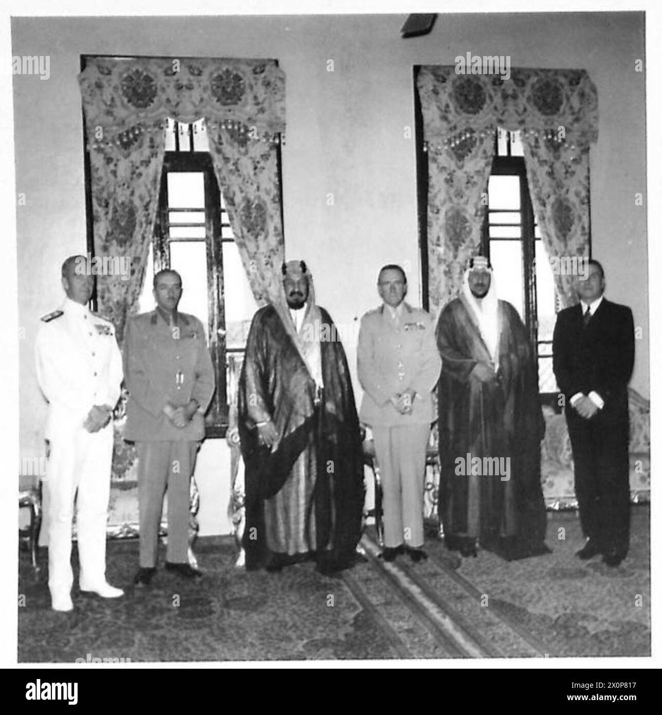 Un groupe comprenant le vice-amiral W.G. Tennant, le maréchal Lord Alanbrooke, le roi Abd al-'Aziz Ibn Saoud, le général Sir Bernard Paget, le prince héritier et le ministre britannique en Arabie saoudite, Mr. L. Grafftey, est montré au palais de Djeddah. La photographie documente les interactions des dirigeants diplomatiques et militaires. Banque D'Images