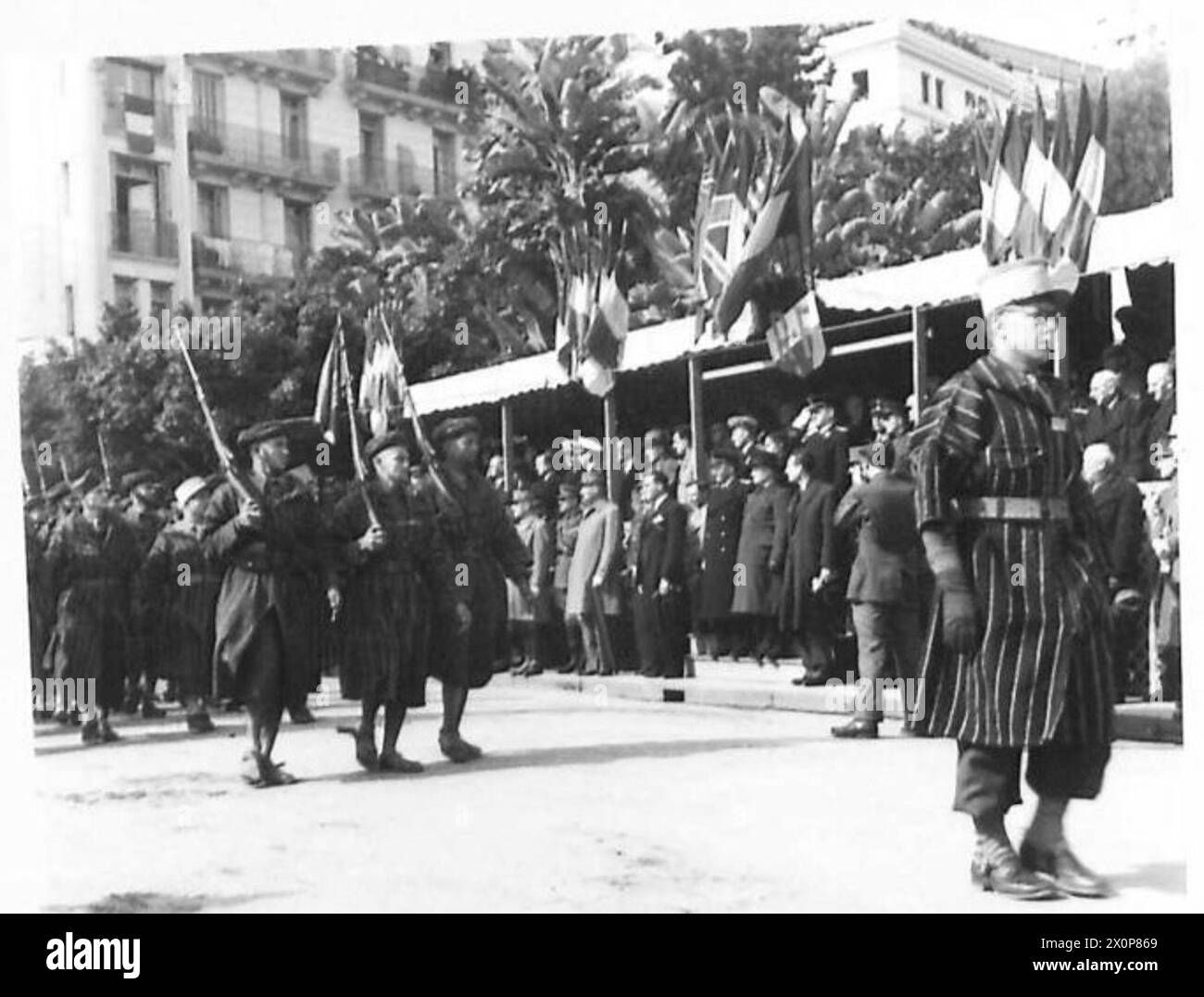 Goumiers de l'armée française défilent devant une base de salutation lors des célébrations de la Journée de l'armée rouge à Alger, documentées dans un négatif photographique de l'armée britannique. Banque D'Images