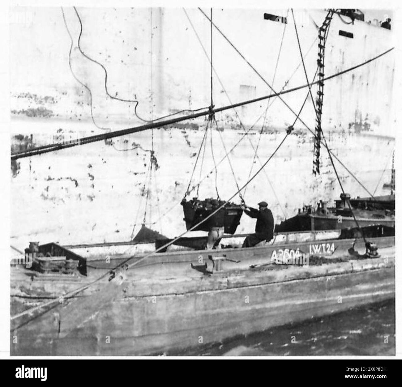 Un petit wagon basculant décharge du charbon sur un briquet à côté d'un Liberty ship, complétant la pince mécanique. Négatif photographique, armée britannique. Banque D'Images