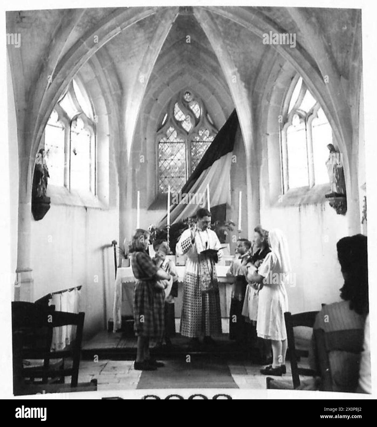 MATERNITÉ BENOUVILLE - les bébés sont baptisés dans la chapelle rattachée à l'hôpital. Dans ces images Abba Saint, Jean, cure de Bhainville, Calvados, baptise certains des nouveaux-nés dans la chapelle. Les bébés sont détenus par des infirmières et d'autres mères, car les leurs sont toujours incapables de sortir du lit. Pendant tout le temps que cette cérémonie se déroulait, des fusils tiraient et les fenêtres de la chapelle cliquetaient. Négatif photographique, Armée britannique, 21e groupe d'armées Banque D'Images