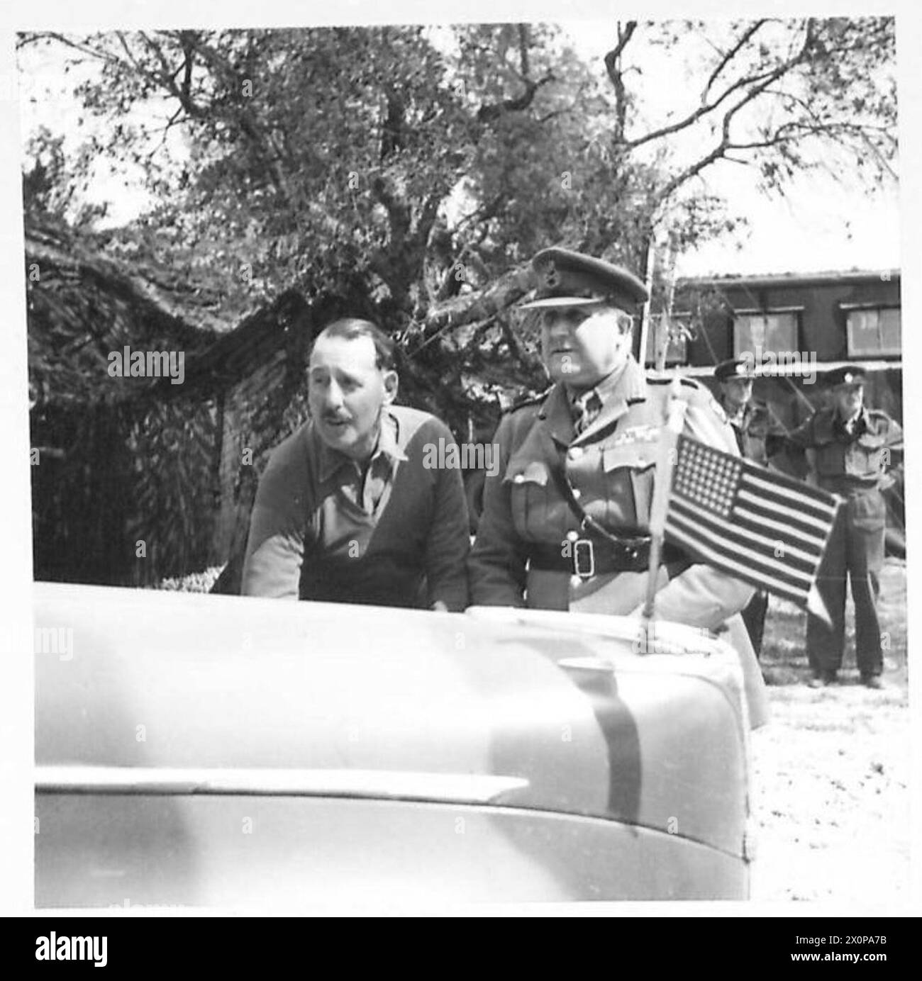 Photographie montrant les généraux Wilson et Leese discutant de la situation au combat avec des cartes sur le capot de la voiture du C-en-C, qui arbore les drapeaux de la Grande-Bretagne, de l'Amérique et de la Pologne lors d'une visite à la 8e armée britannique en Italie. Banque D'Images