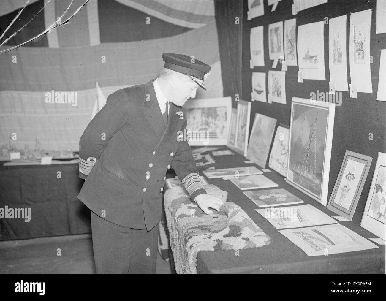 C IN C HOME FLEET JUGE DE L'EXPOSITION D'ART ET D'ARTISANAT DE LA MARINE. DÉCEMBRE 1943, SCAPA FLOW. L'AMIRAL BRUCE FRASER A ÉTÉ L'UN DES JUGES D'UNE EXPOSITION SUR LES ARTS ET L'ARTISANAT, LE TRAVAIL DES HOMMES ET DES OFFICIERS DE LA FLOTTE LOCALE. - L'amiral Sir Bruce Fraser inspecte certaines des pièces Banque D'Images