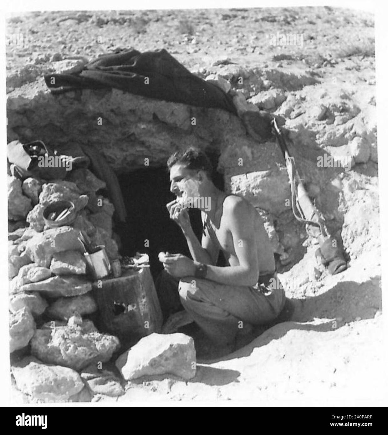 Soldat se rasant à l'extérieur de sa grotte endormie tôt le matin. Négatif photographique, armée britannique. Banque D'Images