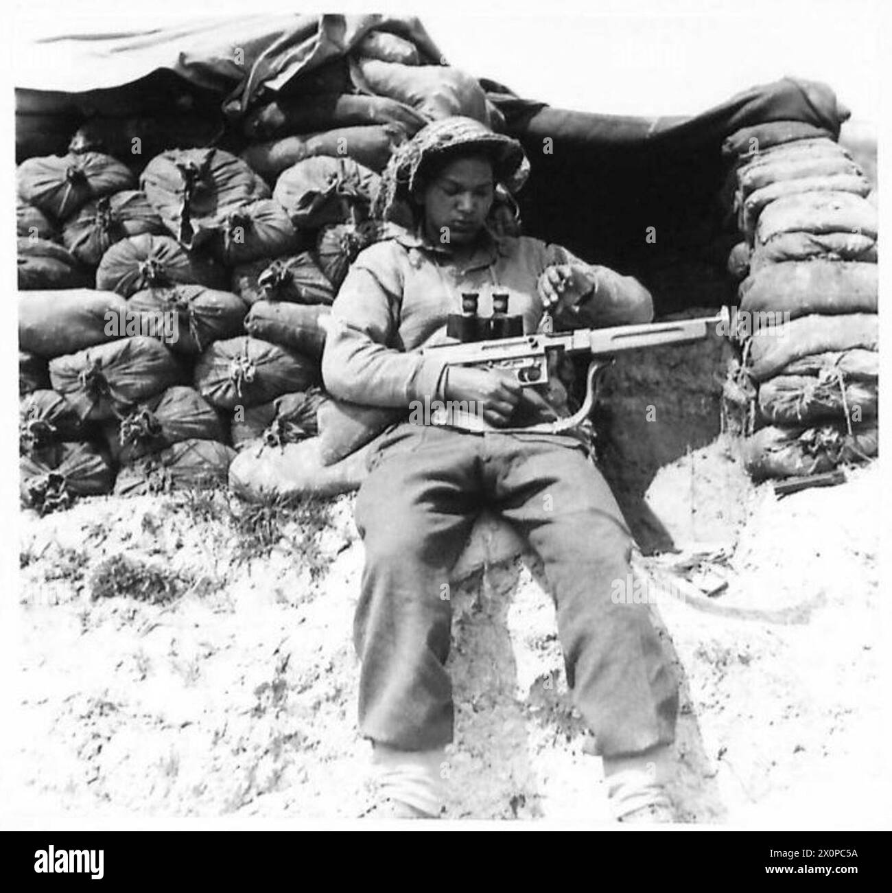 L/Nayak Surendar Sing Rawat de la 8e armée nettoie son fusil Tommy après une patrouille où il a recueilli des renseignements sur les mouvements ennemis alors qu'il était temporairement abrité par des civils. Il sert dans les 3/18 Royal Garhwal Rifles, 25e brigade, 10e division indienne. Banque D'Images