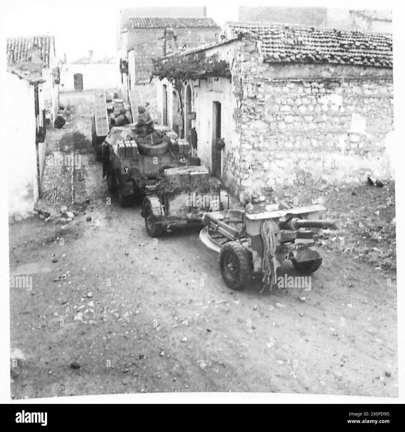 Un canon d'artillerie de 25 livres avance avec les troupes de la 8e armée à travers une rue baignée de pluie en Italie. Le mouvement est capturé dans un négatif photographique par l'armée britannique. Banque D'Images