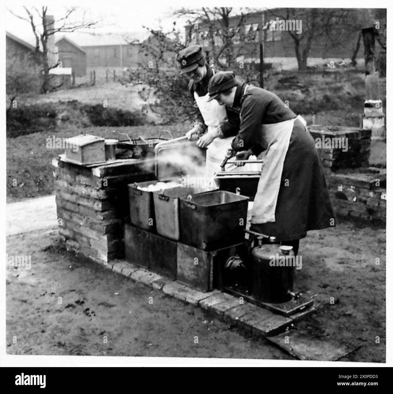 Dans une A.T.S. School of Cookery, la nourriture est préparée sur une cuisinière de terrain, capturée dans un négatif photographique de l'armée britannique. Banque D'Images