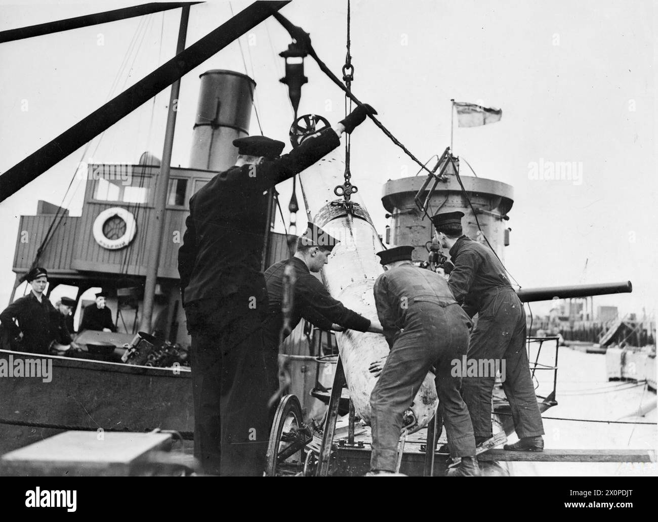 « BLIND SUBMARINE » REVIENT À LA MAISON. LES 3 ET 4 AVRIL 1943, PORTSMOUTH, LE SOUS-MARIN BRITANNIQUE URSALA QUI A NAVIGUÉ « À L'AVEUGLE » PENDANT SIX JOURS ET SIX NUITS AVEC SON PÉRISCOPE ÉCRASÉ APRÈS AVOIR ÉTÉ PERCUTÉ PAR UN DESTROYER ENNEMI, EST MAINTENANT DE RETOUR CHEZ LUI. - Torpilles en cours de chargement à bord de l'URSALA. Malgré leur taille, ils peuvent être accrochés à bord, glissés à travers la trappe avant et placés en position dans leurs tubes en un peu plus de 5 minutes Banque D'Images