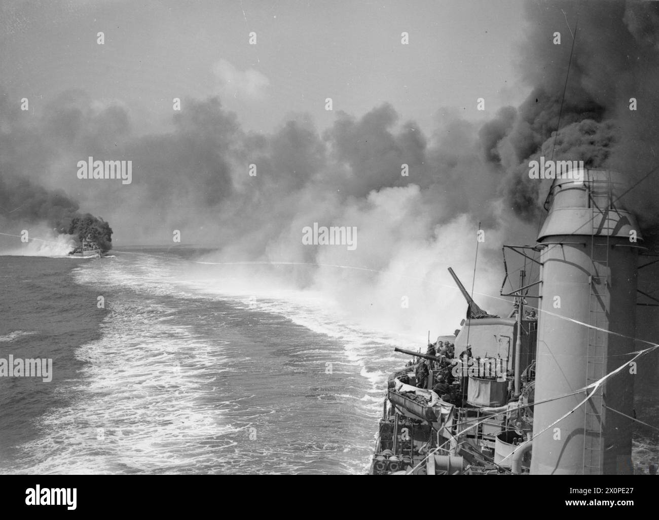 Le HMS DIDO, un croiseur de la Royal Navy, bombarde les batteries ennemies, les décharges de munitions et les routes à l'ouest de Gaeta, en Italie, pendant la seconde Guerre mondiale, observé depuis le destroyer américain MACKENZIE. Banque D'Images