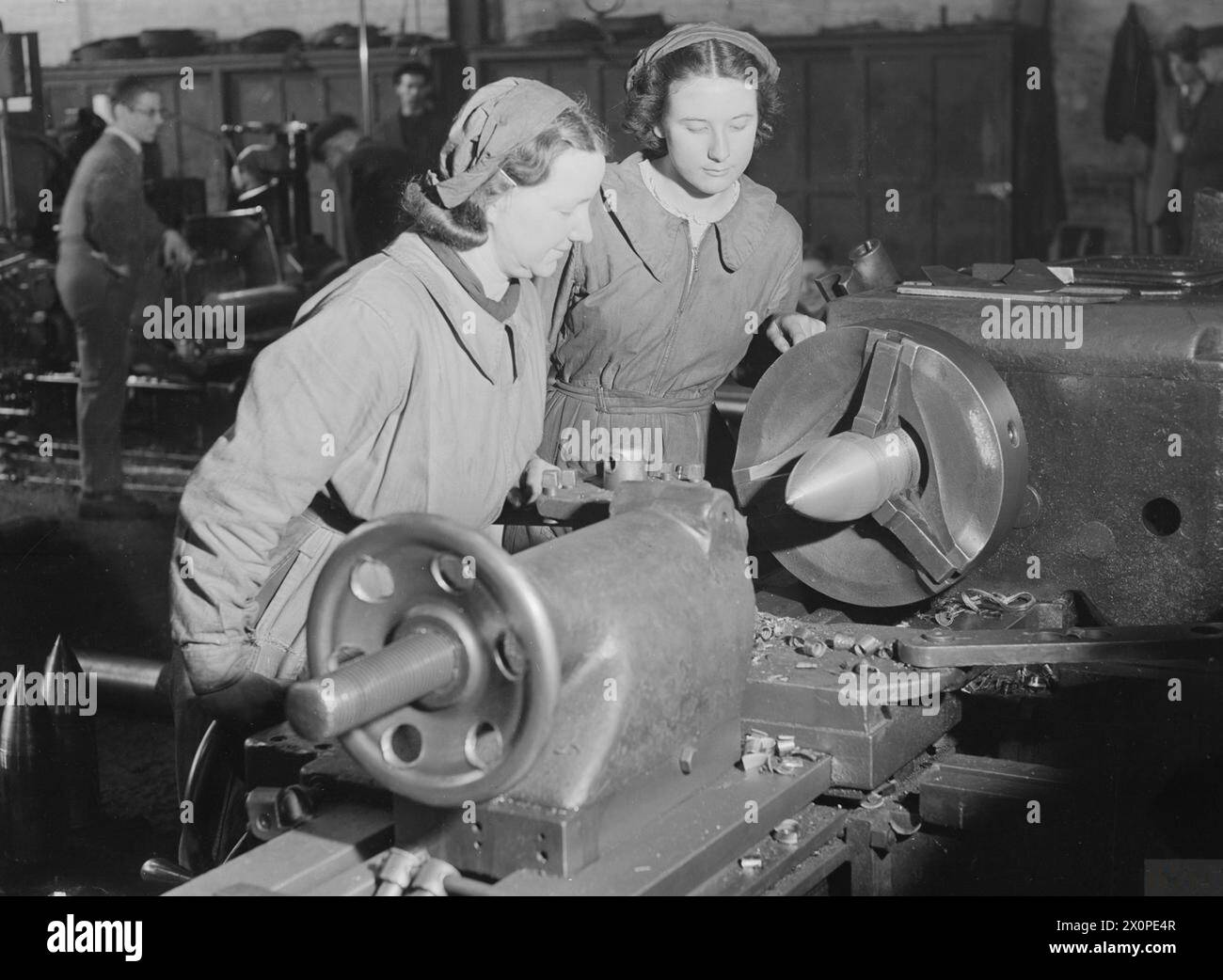 Femmes dans l'industrie en 1939-1945, mère et fille conduisant une machine de peinture d'obus dans une usine de munitions de Sheffield. Banque D'Images