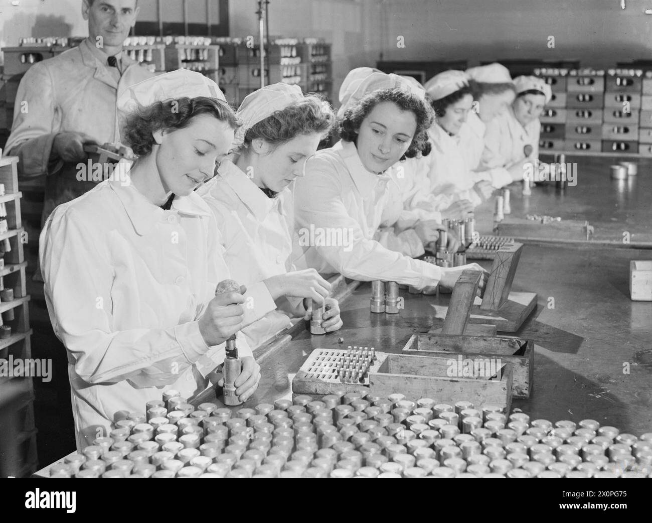 Les femmes à temps partiel, connues sous le nom de « Housewives Brigade », travaillent dans une usine de remplissage de coquilles Royal Ordnance produisant des fusibles, portant un badge rouge, blanc et bleu pour se distinguer des travailleurs à plein temps, 1939-1945. Banque D'Images