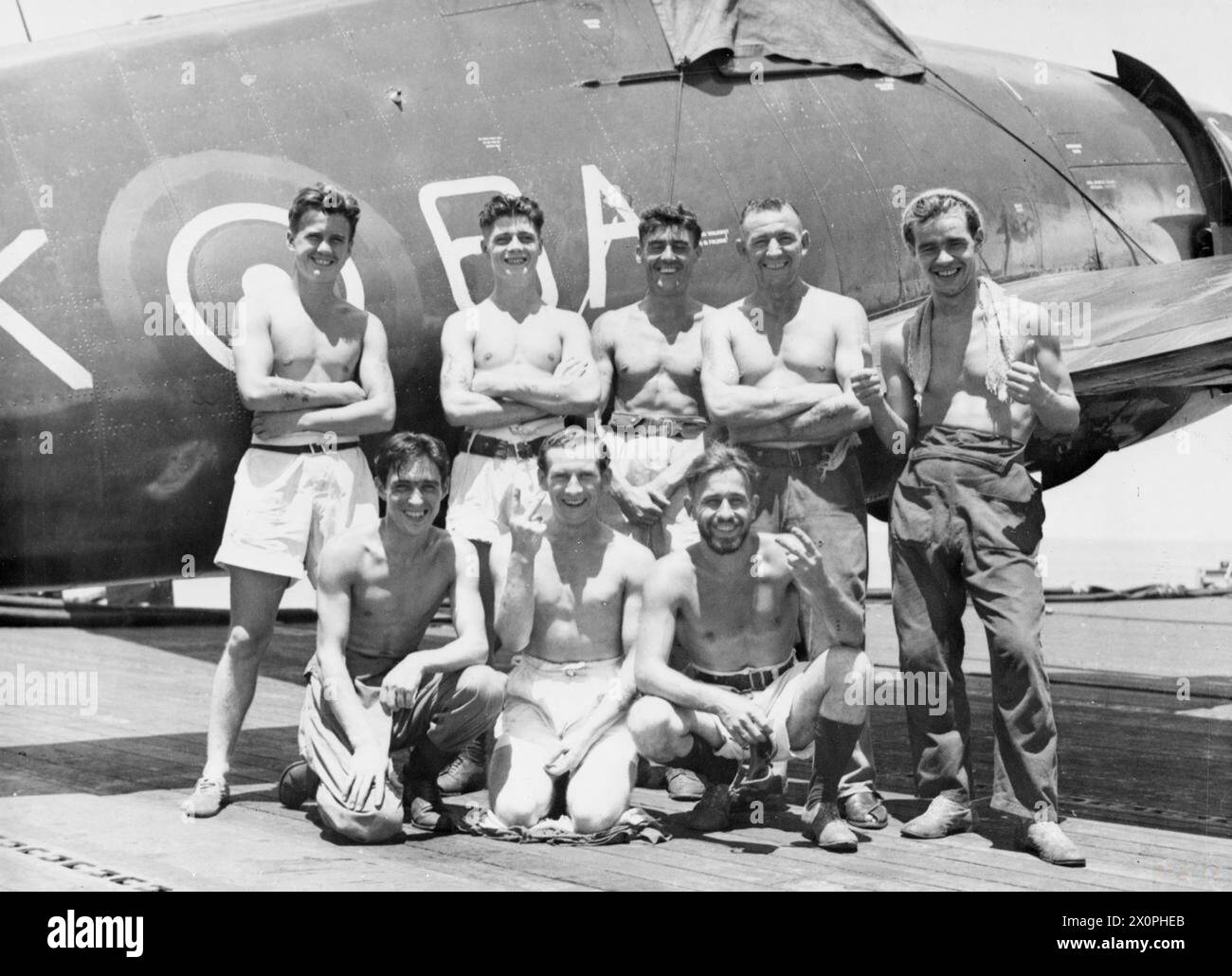 HOMMES D'UN PORTE-AVIONS D'ESCORTE DANS LES EAUX ORIENTALES. AVRIL 1945, À BORD DU PORTE-AVIONS D'ESCORTE HMS KHEDIVE. - Huit hommes de Glasgow servant dans le KHÉDIVE debout devant un chasseur de la Hellcat Naval. De gauche à droite : W McCarthy ; d Breckenridge, Maryhill ; A Hunter, Partick West; R Walker ; J McGettigan, Springburn. Première rangée : E Lyons ; W McIntosh, Govan ; A Crook, Mountellen Garteosh, près de Glasgow Banque D'Images