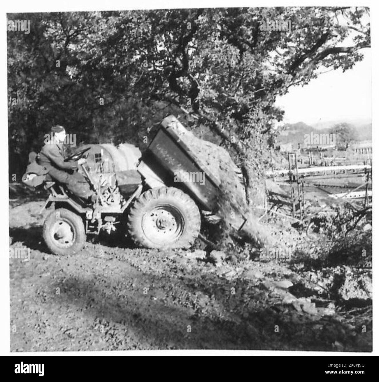Un tombereau de 2 1/2 yards décharge des bardeaux pour élargir une route dans le cadre des opérations d'ingénierie. Banque D'Images
