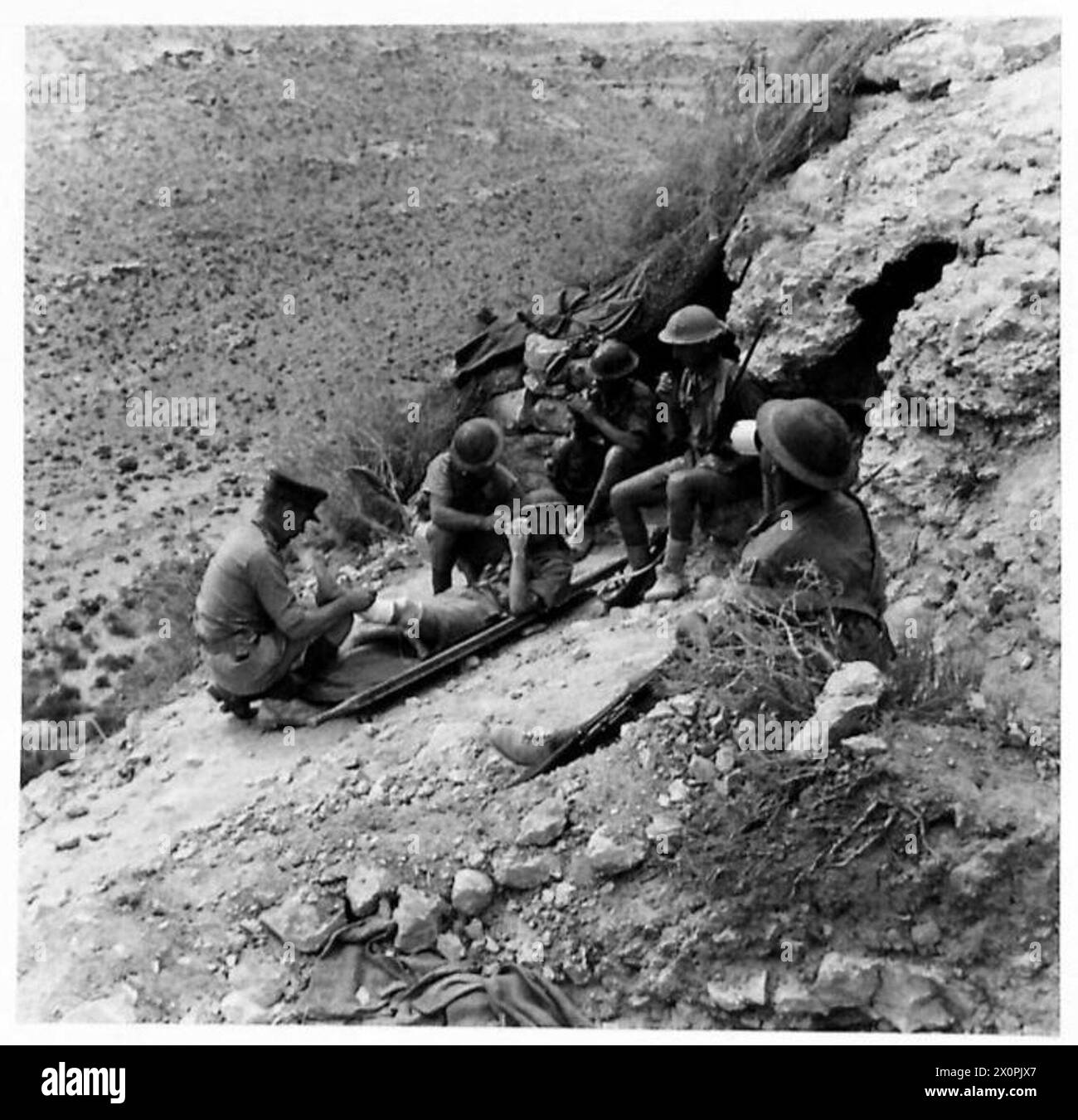 Au cours d'une patrouille Tobrouk à l'aube, l'officier s'occupe d'une victime tandis que la patrouille se repose pour boire et fumer. Banque D'Images